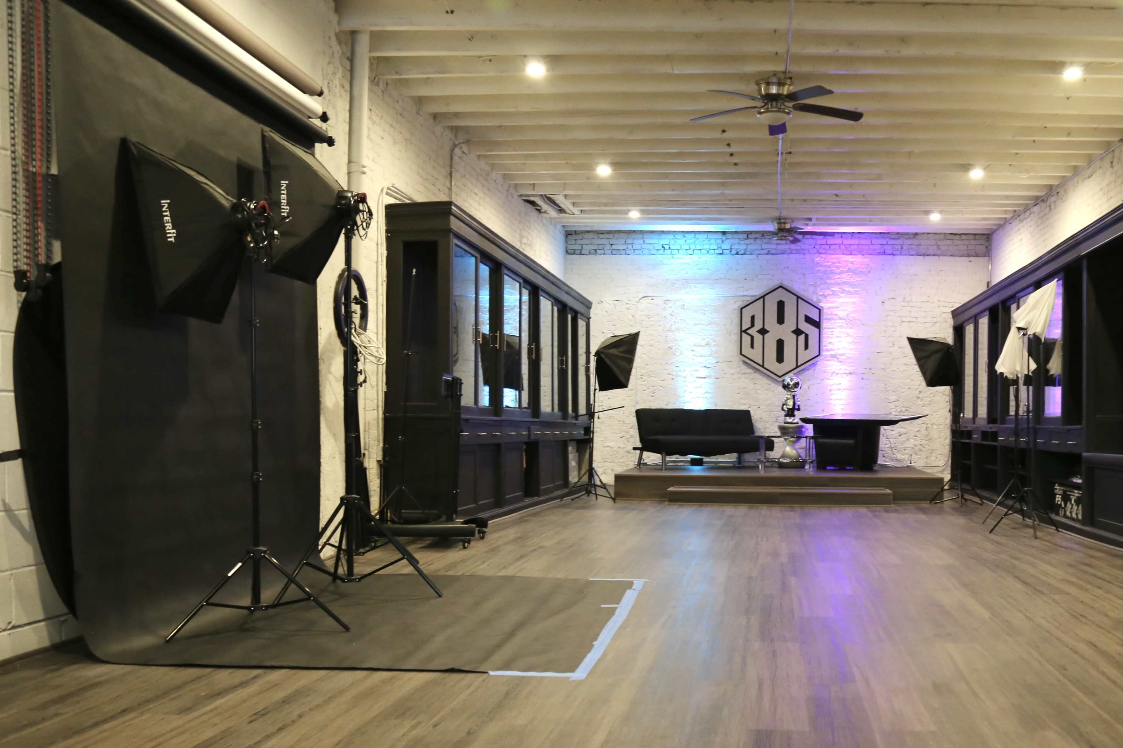 A photography studio with multiple light sources, a dark backdrop, and modern furnishings.