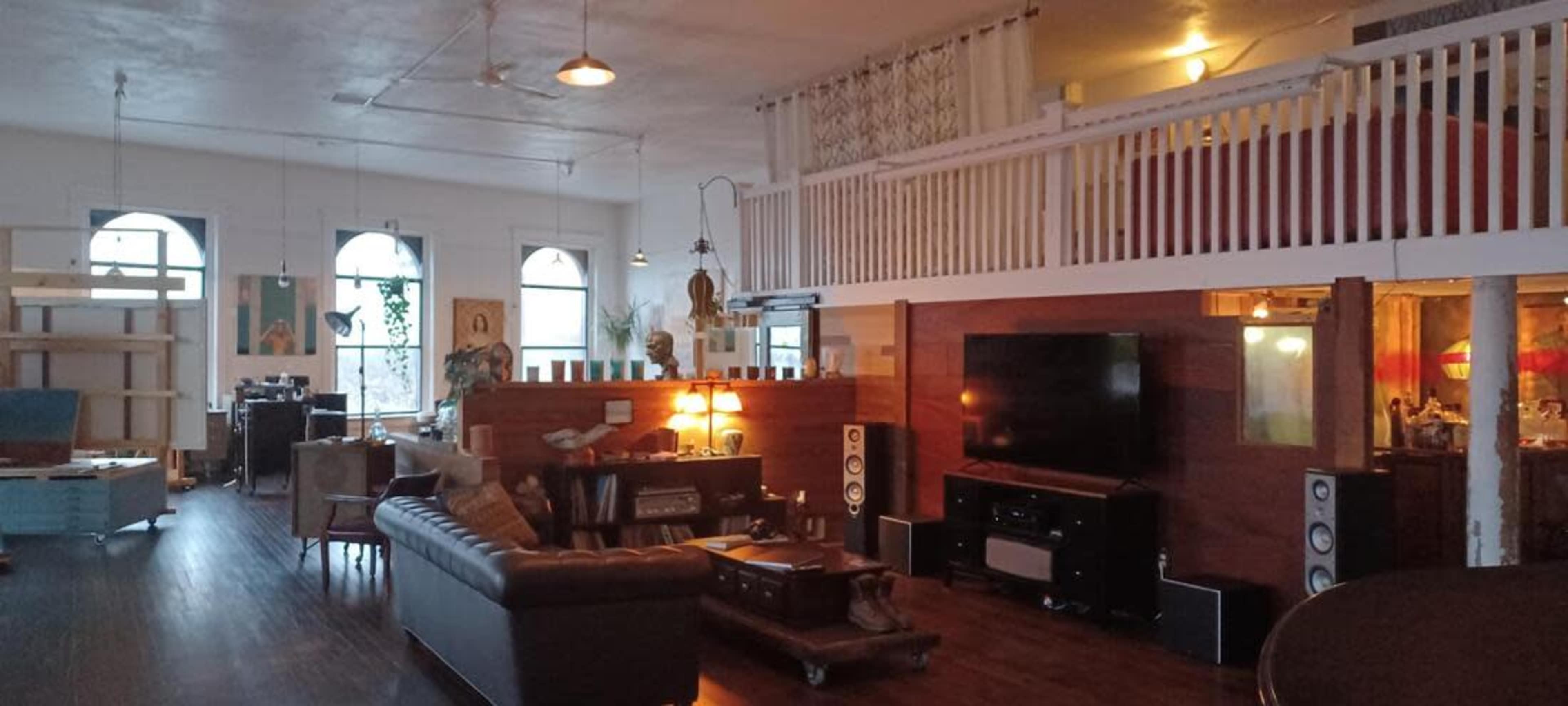 A spacious open-concept living area with a loft, featuring a seating area, a large television, and wooden furnishings.