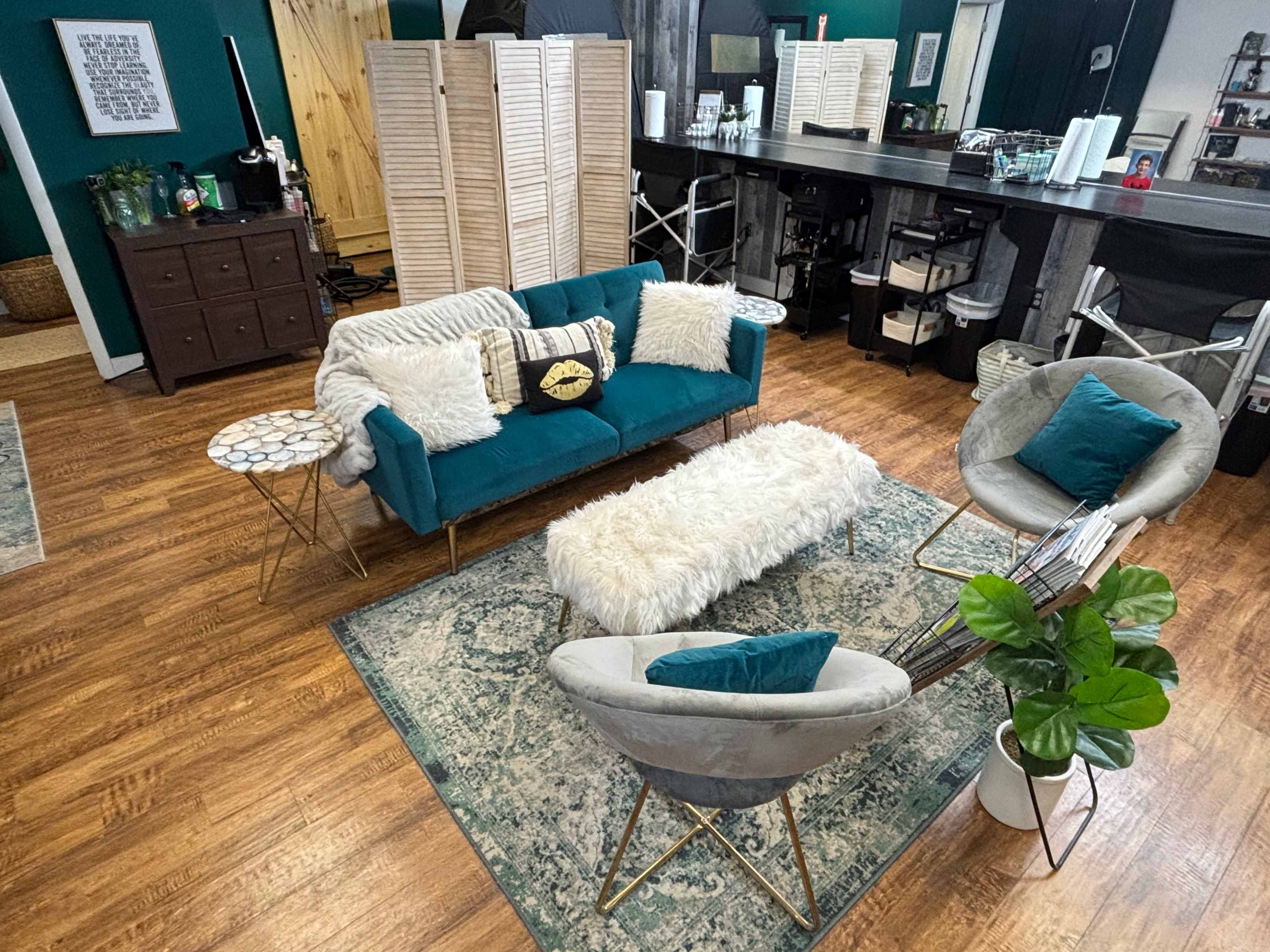 A cozy living space with a teal sofa, two round chairs, a fluffy white coffee table, and a patterned rug on wooden flooring.