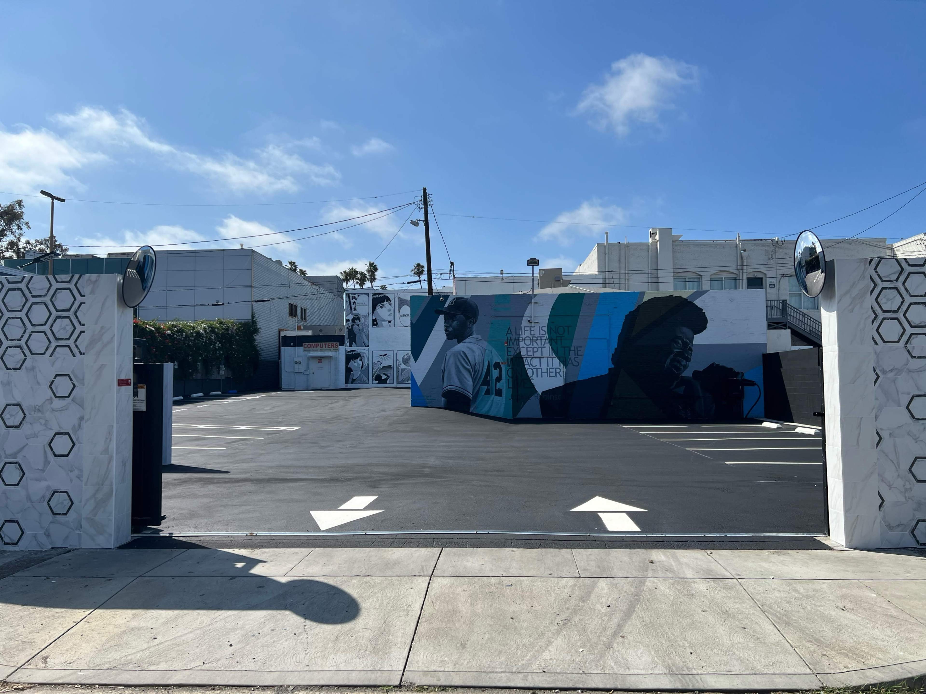 A parking lot featuring a large mural on a wall and directional arrows on the ground.