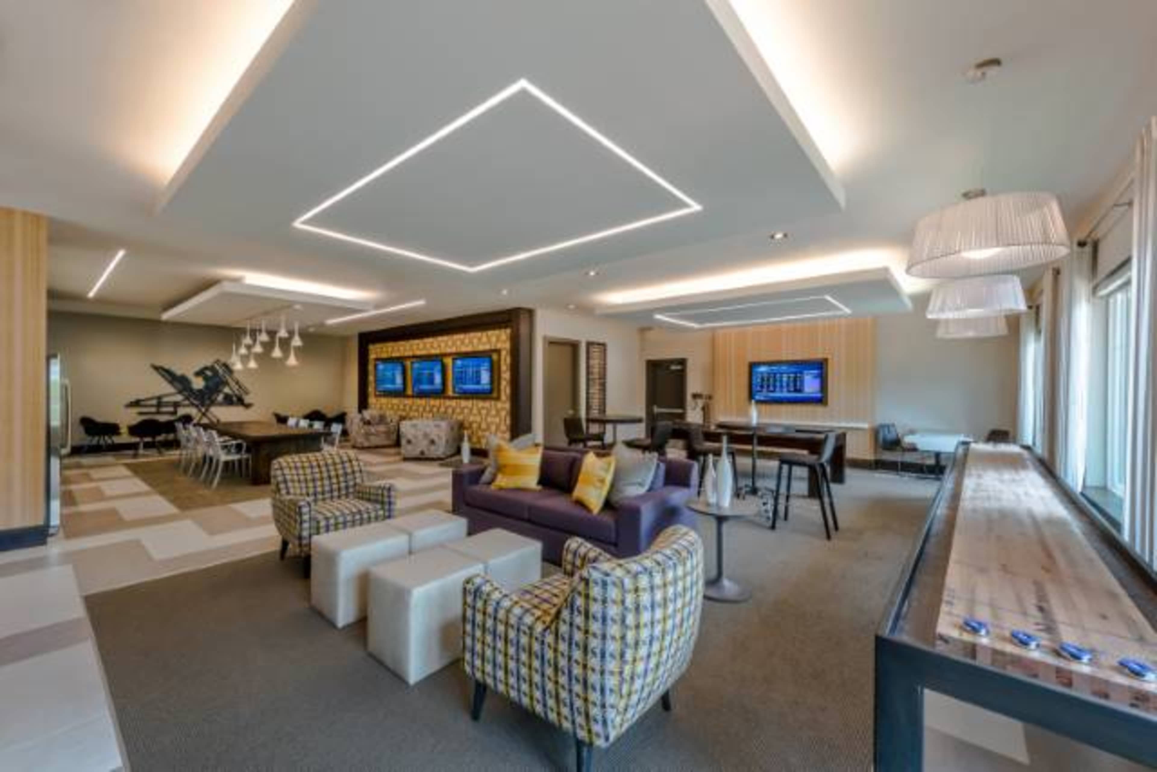 A modern lounge area featuring seating arrangements, flat-screen displays, and ambient lighting.