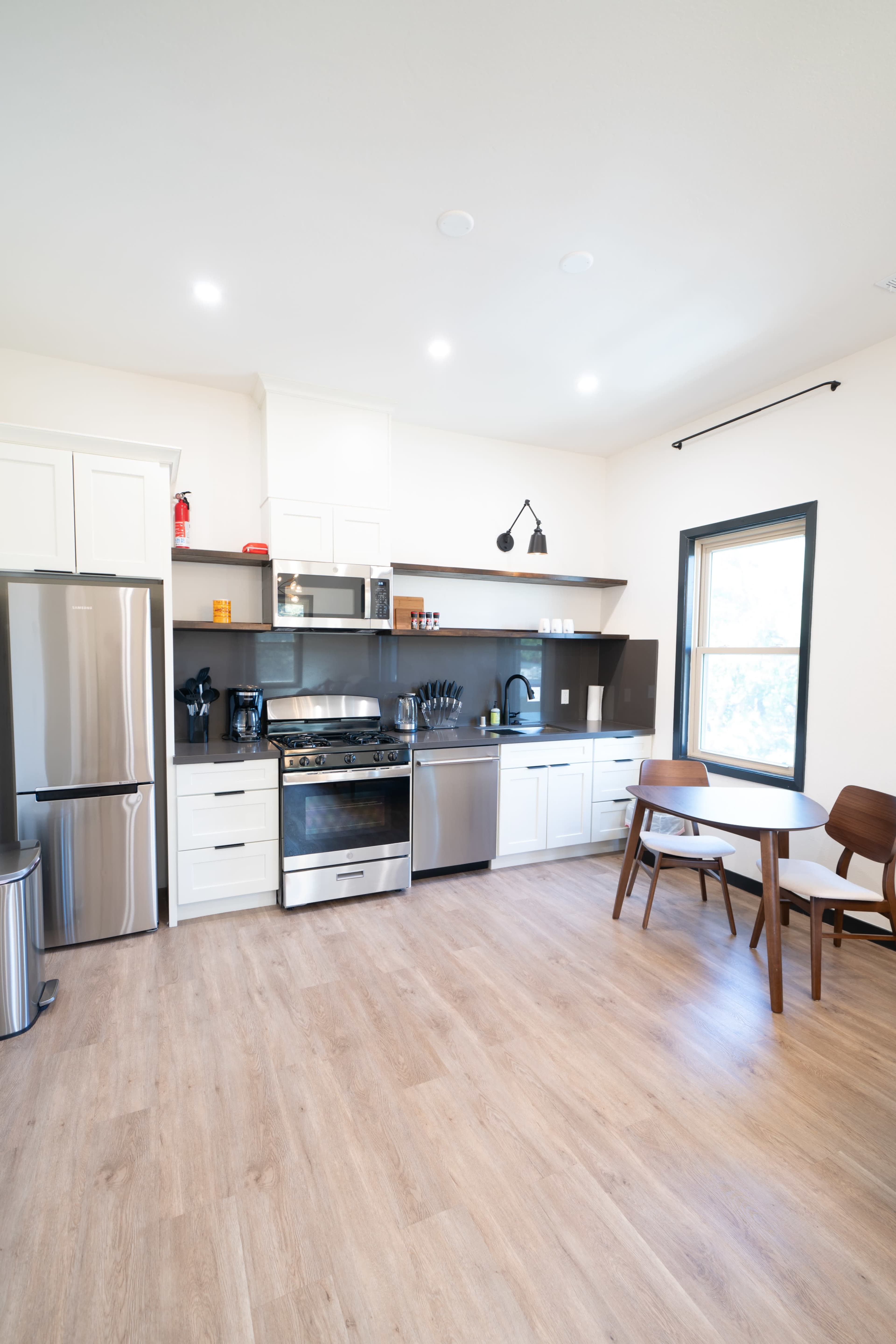 A modern kitchen with stainless steel appliances, white cabinetry, and a wooden dining table.