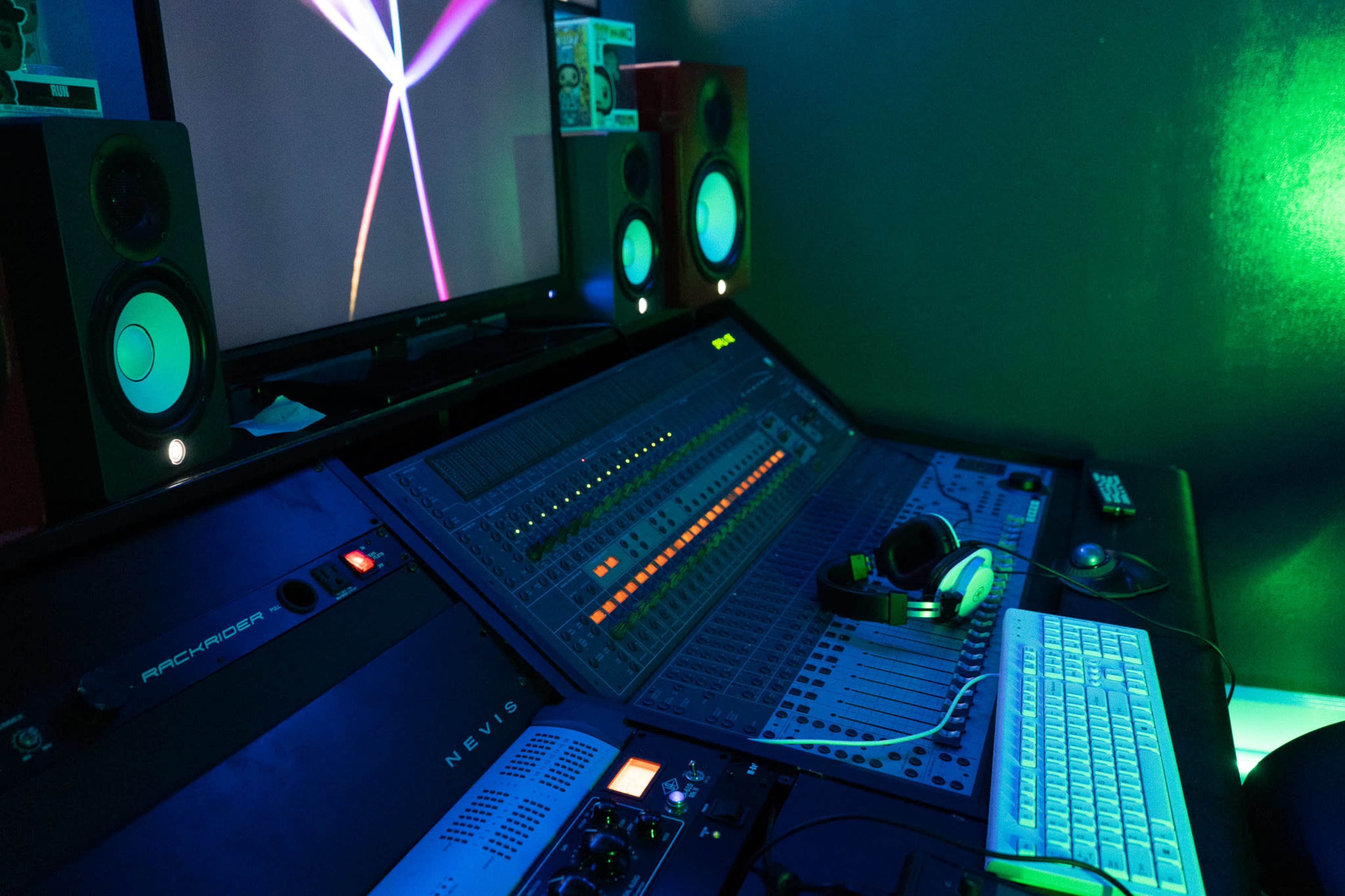 A music production studio with a digital audio workstation, speakers, a computer keyboard, and headphones.