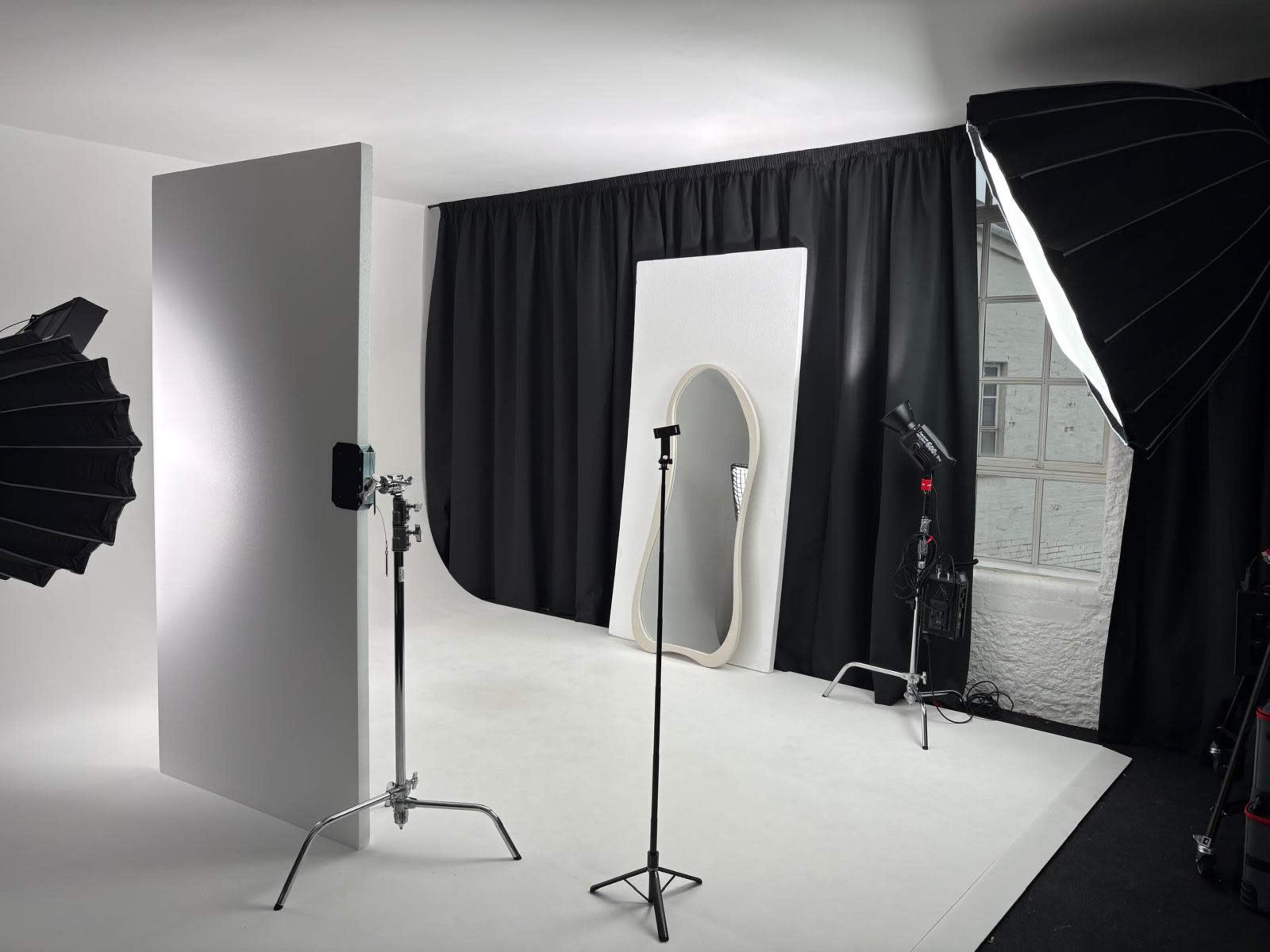 The image shows a photography studio setup with a large mirror, softbox lighting, and a blank backdrop.