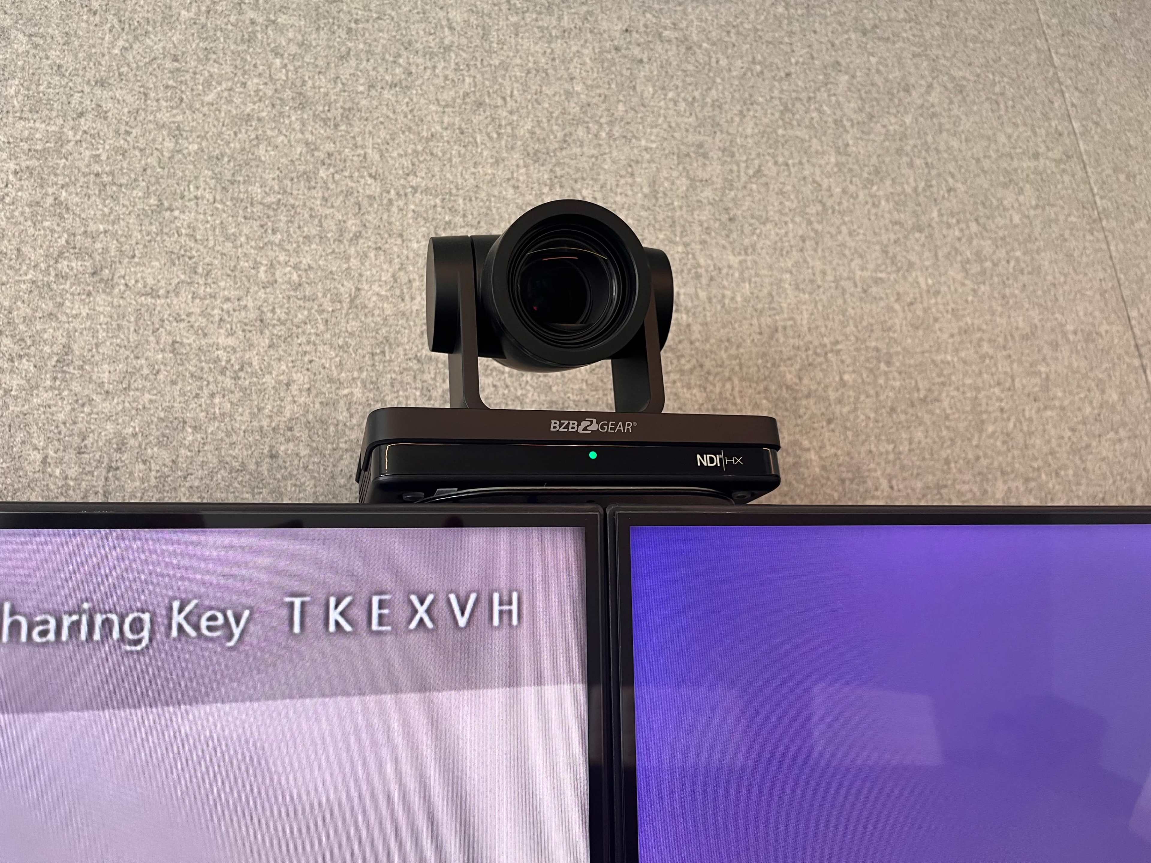 A camera is mounted on top of a display screen, with a connectivity device featuring a sharing key visible below.