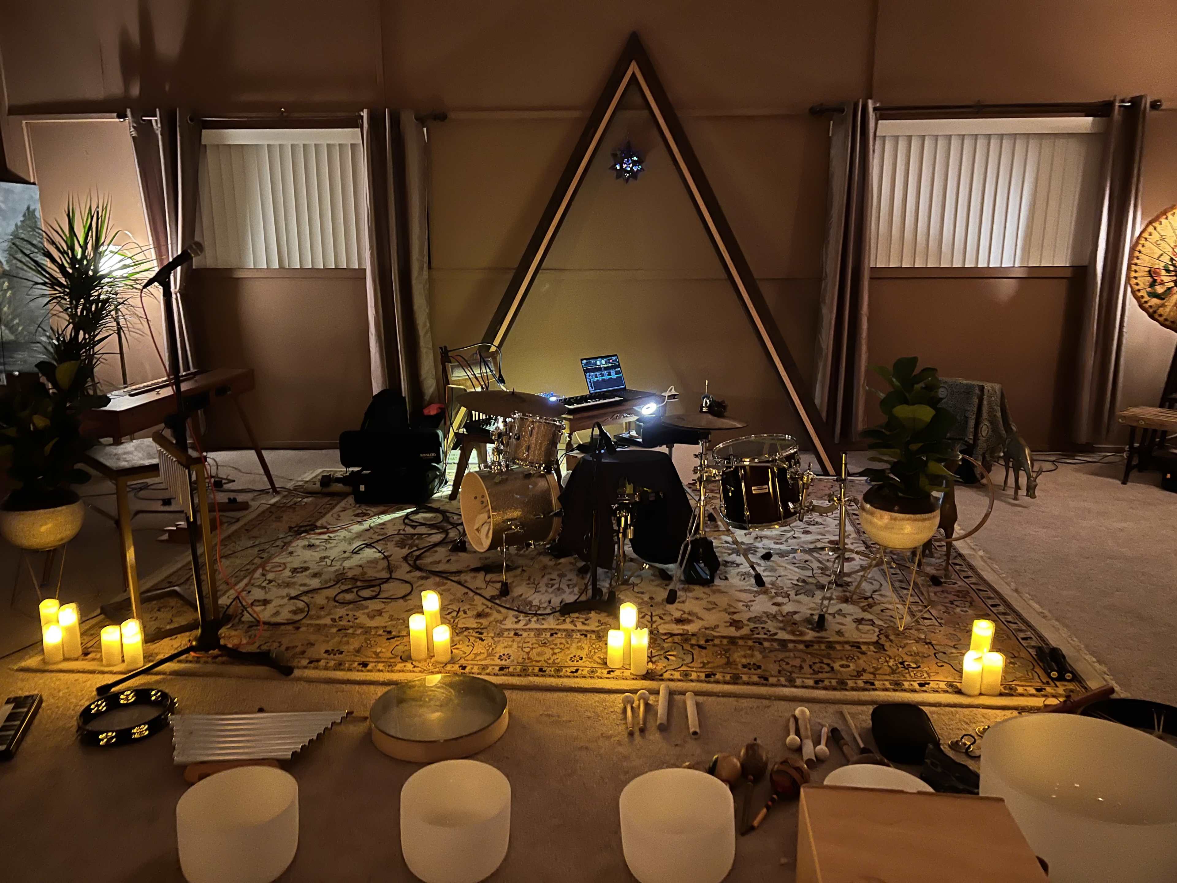 The scene features a dimly lit music space with various instruments arranged around a central triangular formation, illuminated by candles.