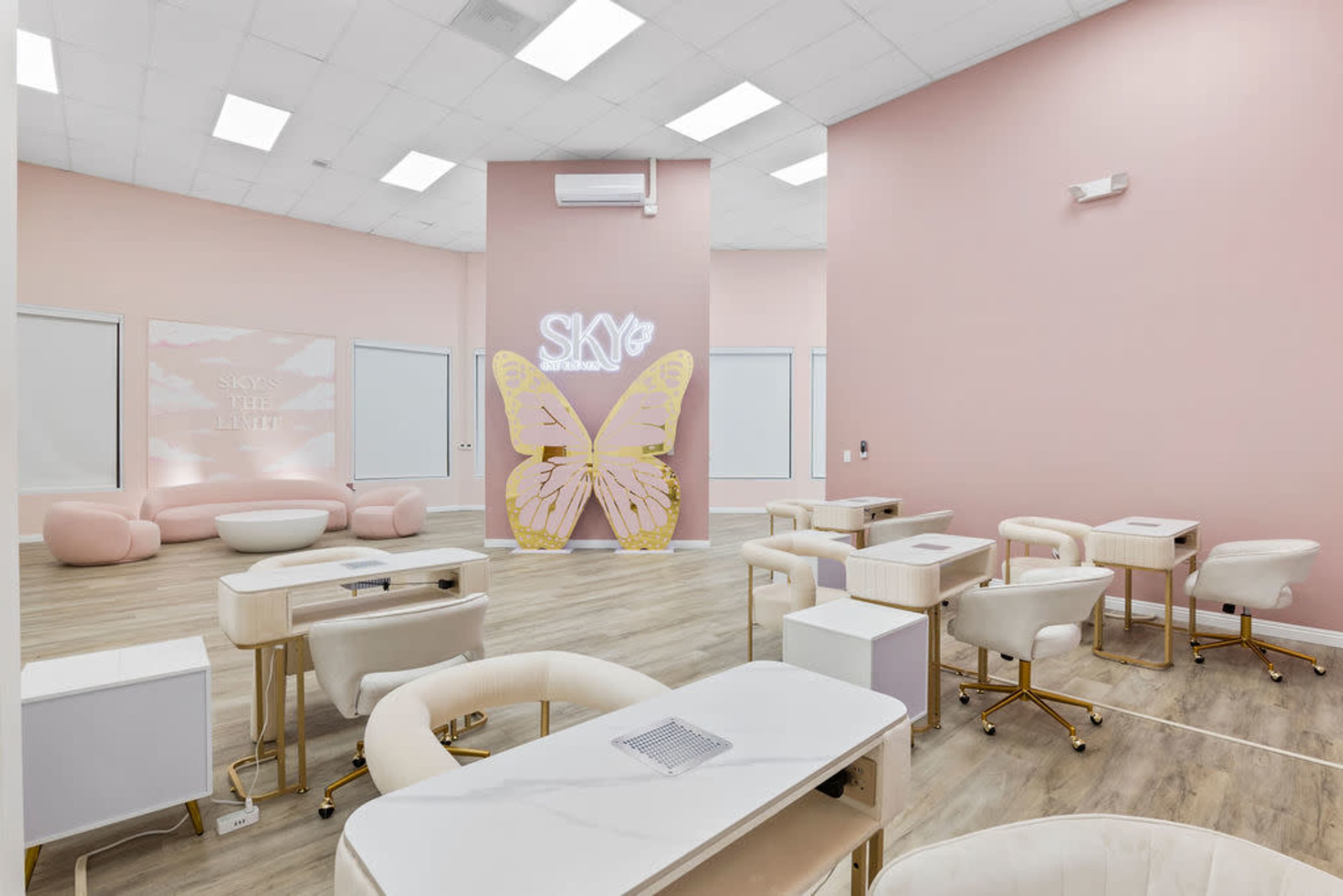 The image shows a modern, pastel-colored salon interior with multiple stylist stations, a butterfly-themed display, and a cozy seating area.