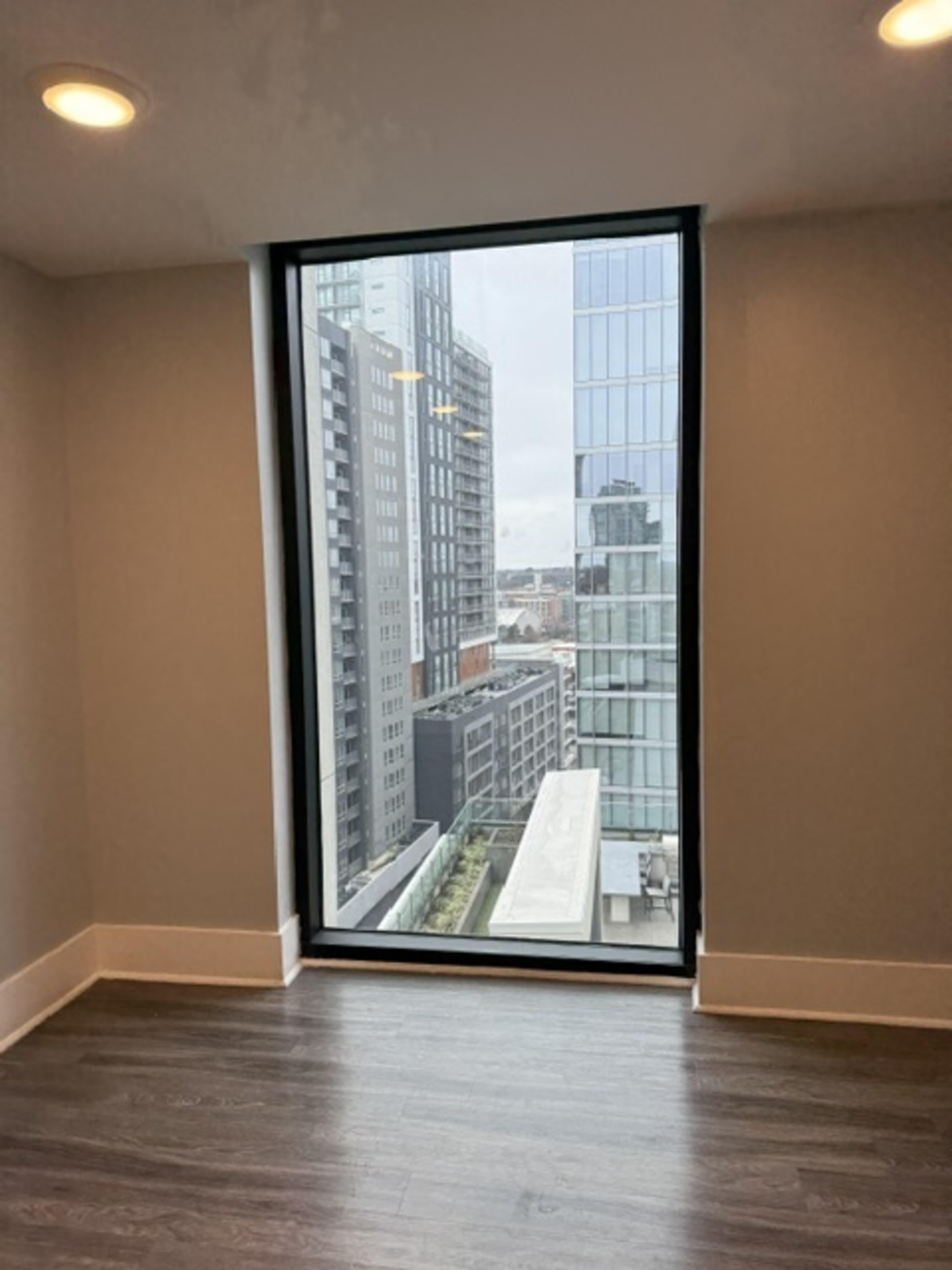A large window frames a view of tall buildings in an urban environment.