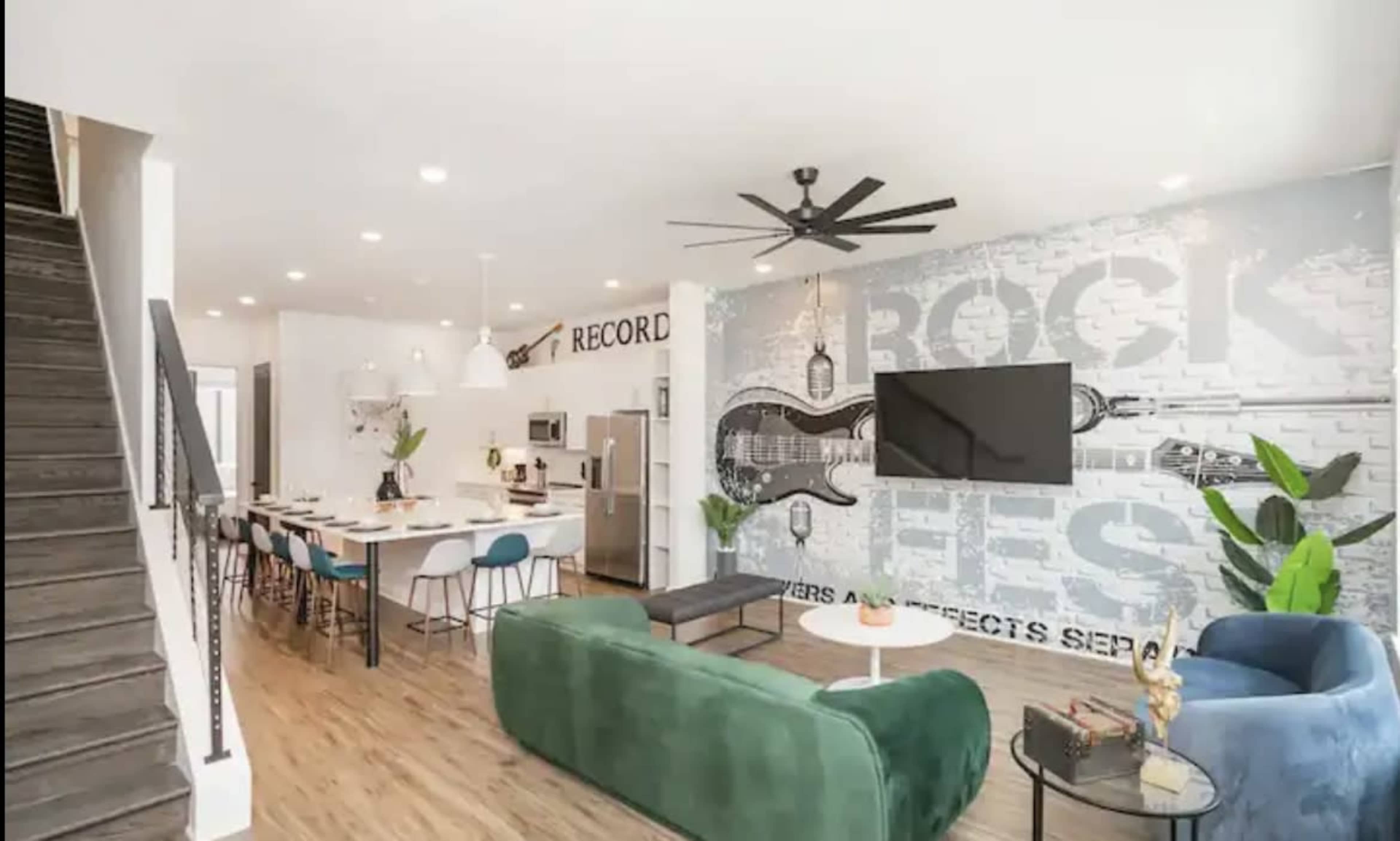 A modern living space with a kitchen area, dining table, and a large wall mural featuring musical elements, complemented by stylish furniture and plants.