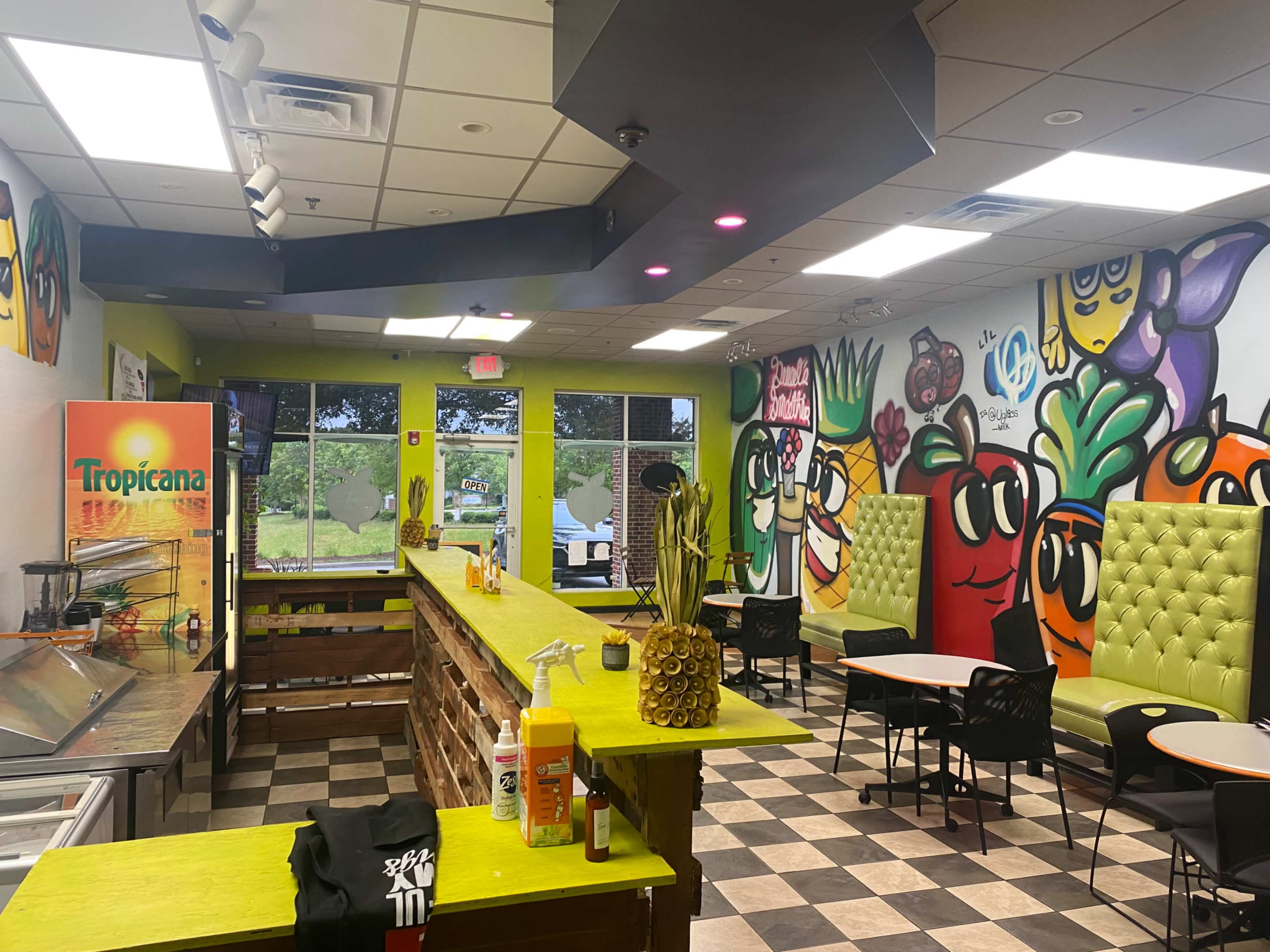 The interior of a vibrant restaurant features colorful murals and green booths with a counter displaying various condiments and drink options.