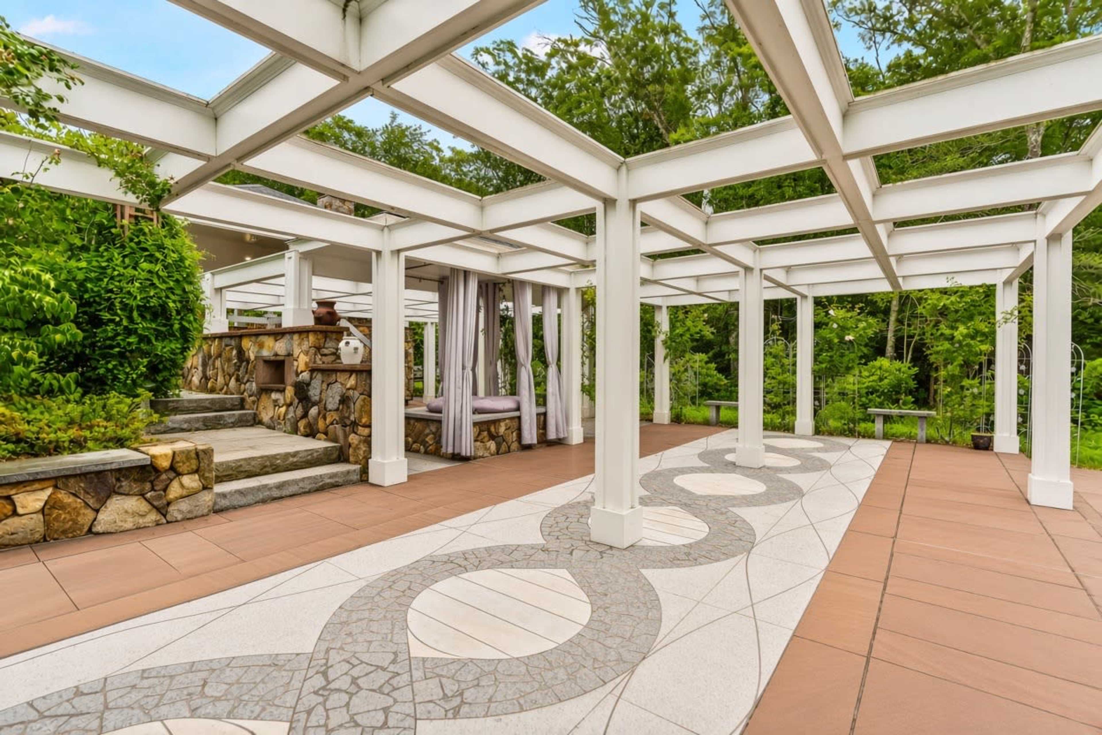 The image shows a spacious outdoor patio with a stone staircase and a decorative pathway surrounded by greenery.