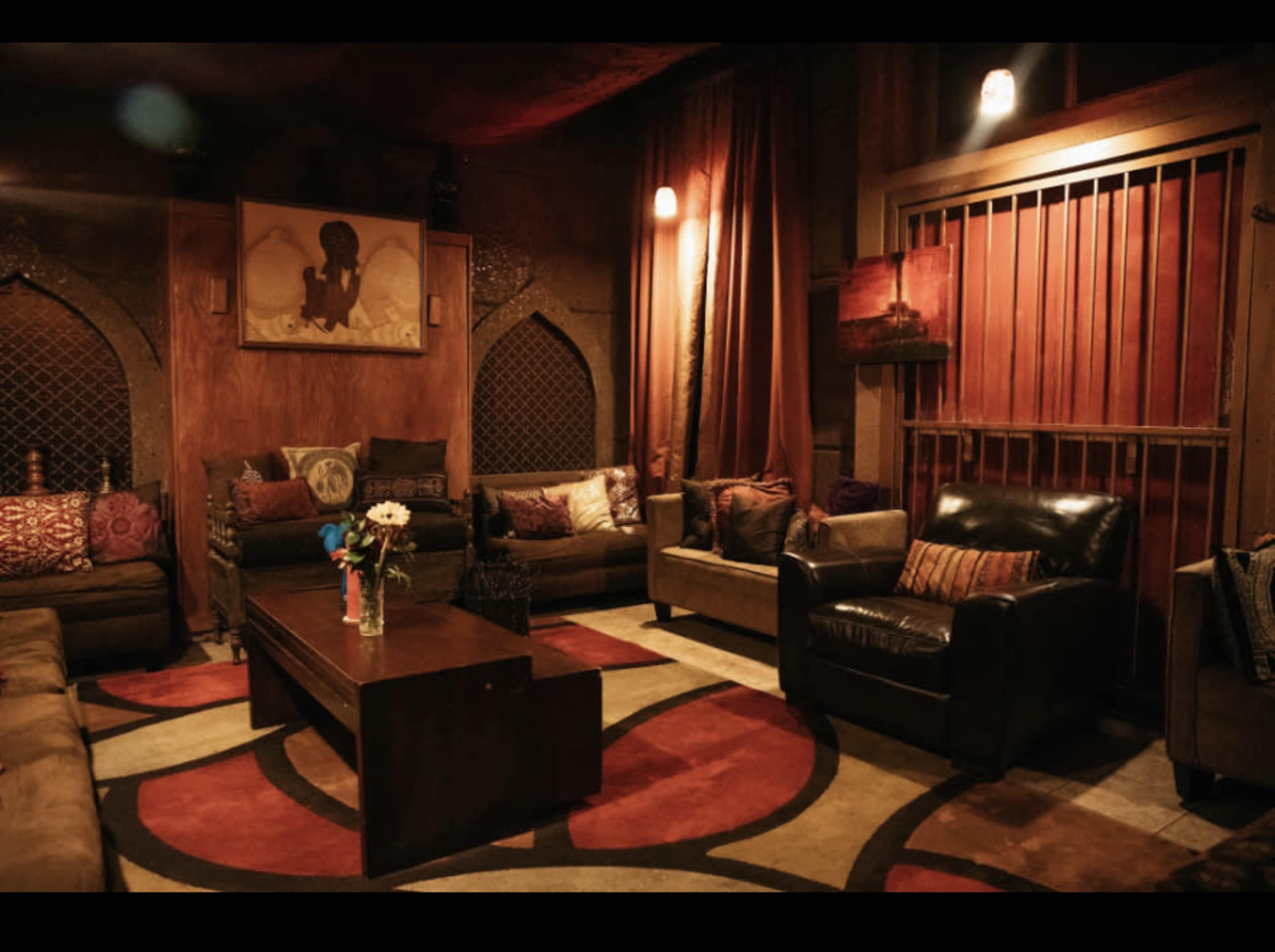 A cozy lounge area features several sofas around a central coffee table, with decorative pillows and warm lighting illuminating the room.