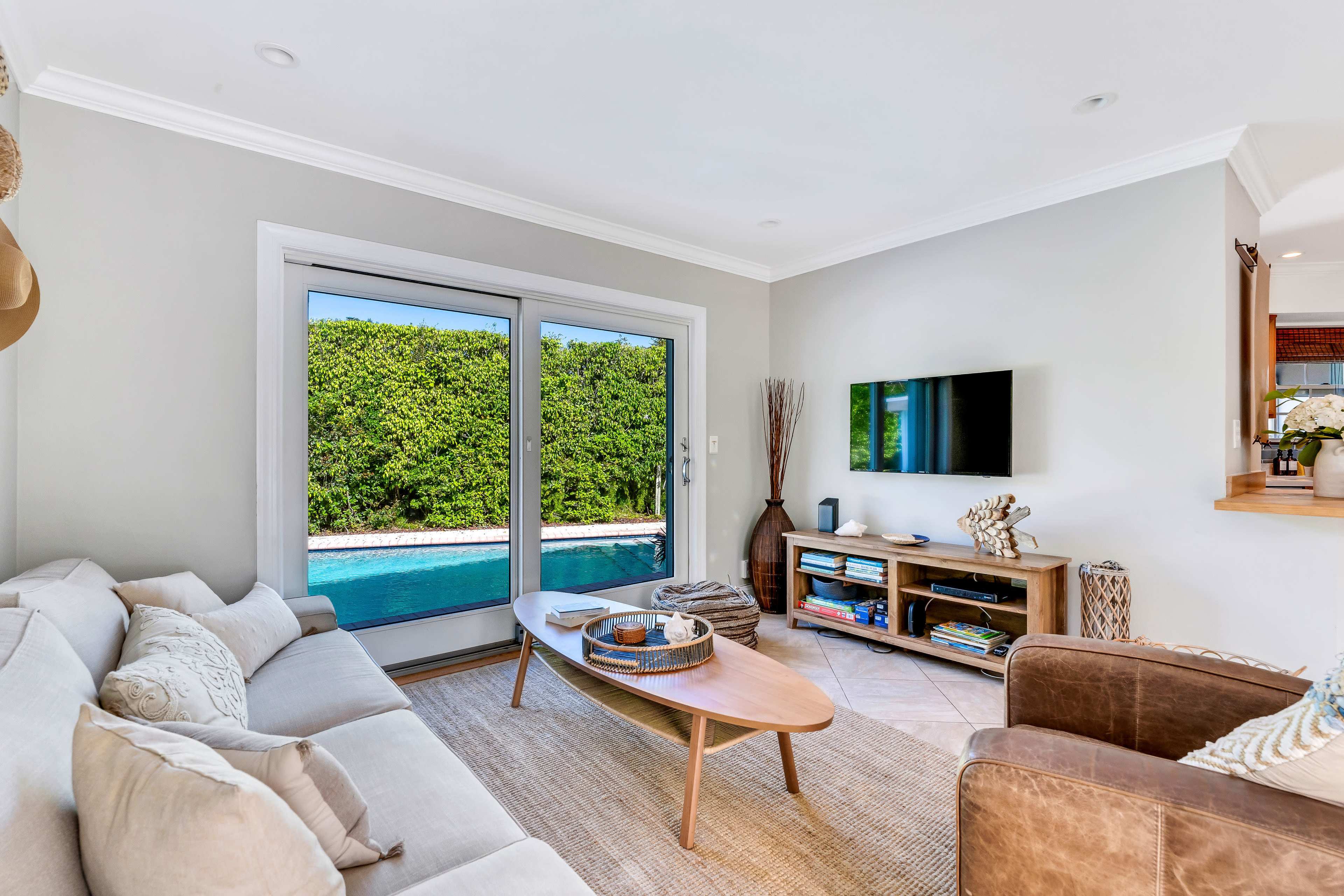 The living room features a couch, a coffee table, and a television, with sliding glass doors leading to an outdoor pool area.