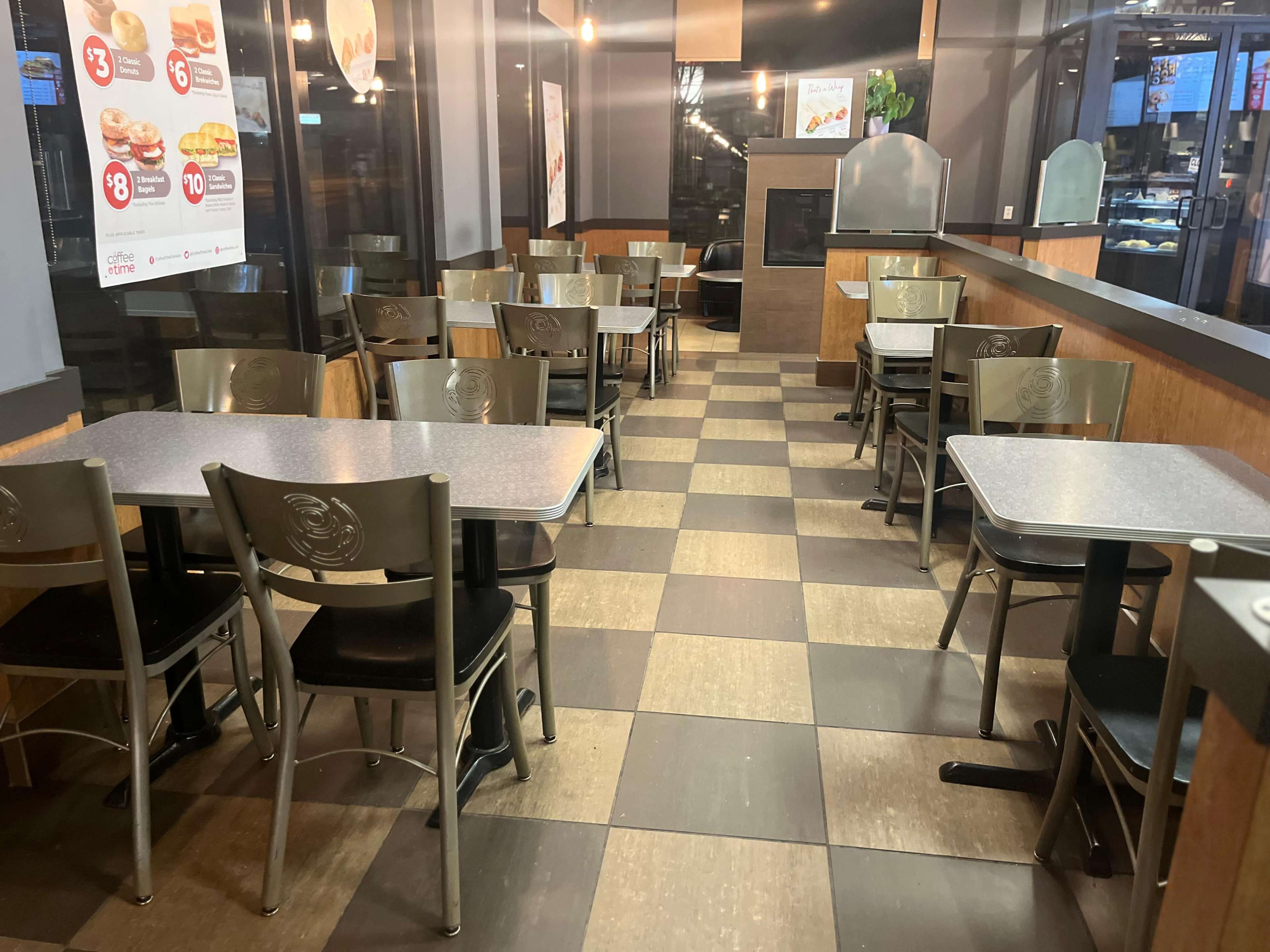 The image shows an empty fast-food restaurant interior with tables and chairs arranged in neat rows and a checkered floor.