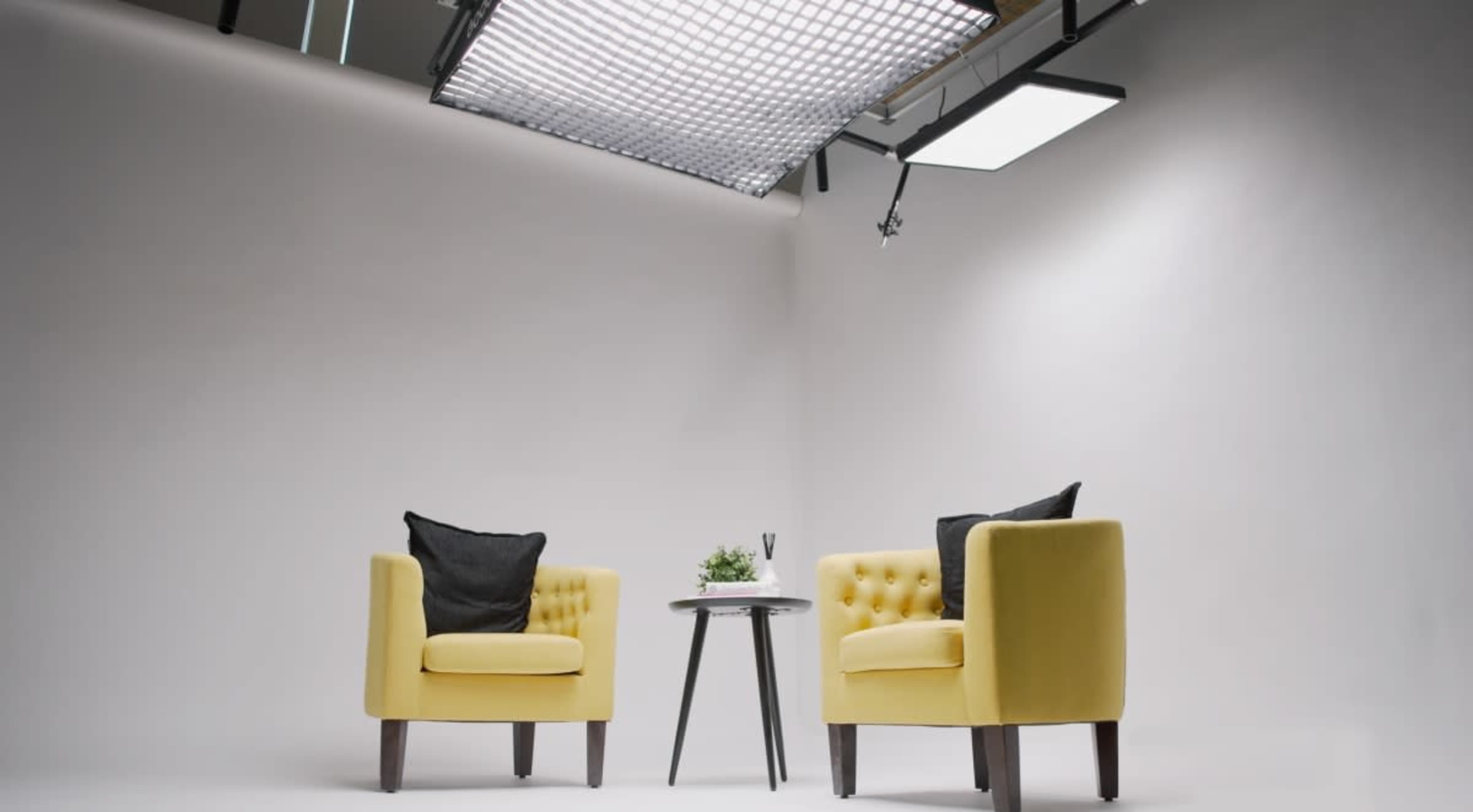 The image shows two yellow armchairs facing each other across a small table on a plain background.