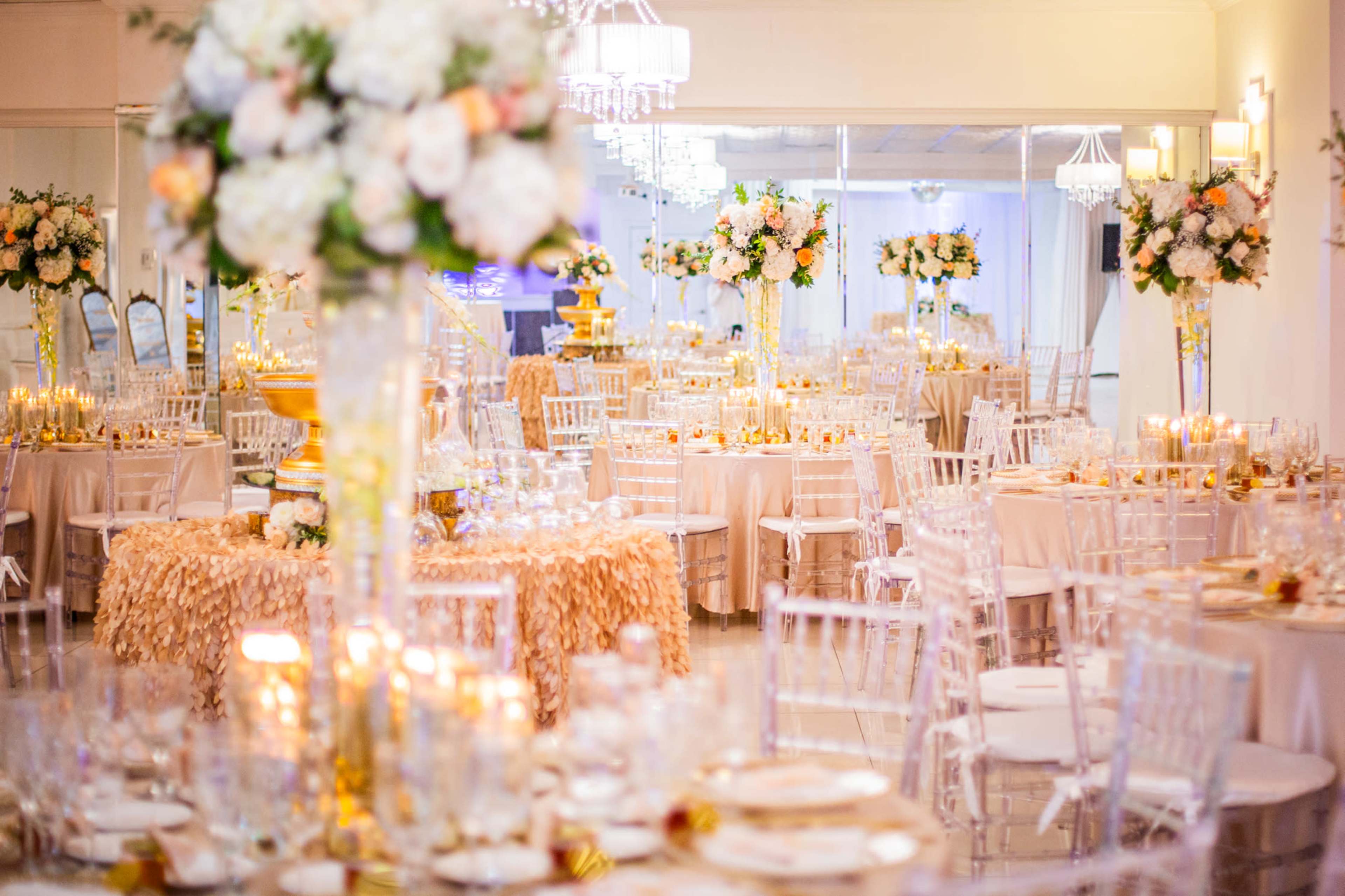The image shows a beautifully arranged banquet hall with elegantly set tables decorated with centerpieces of flowers and candles.