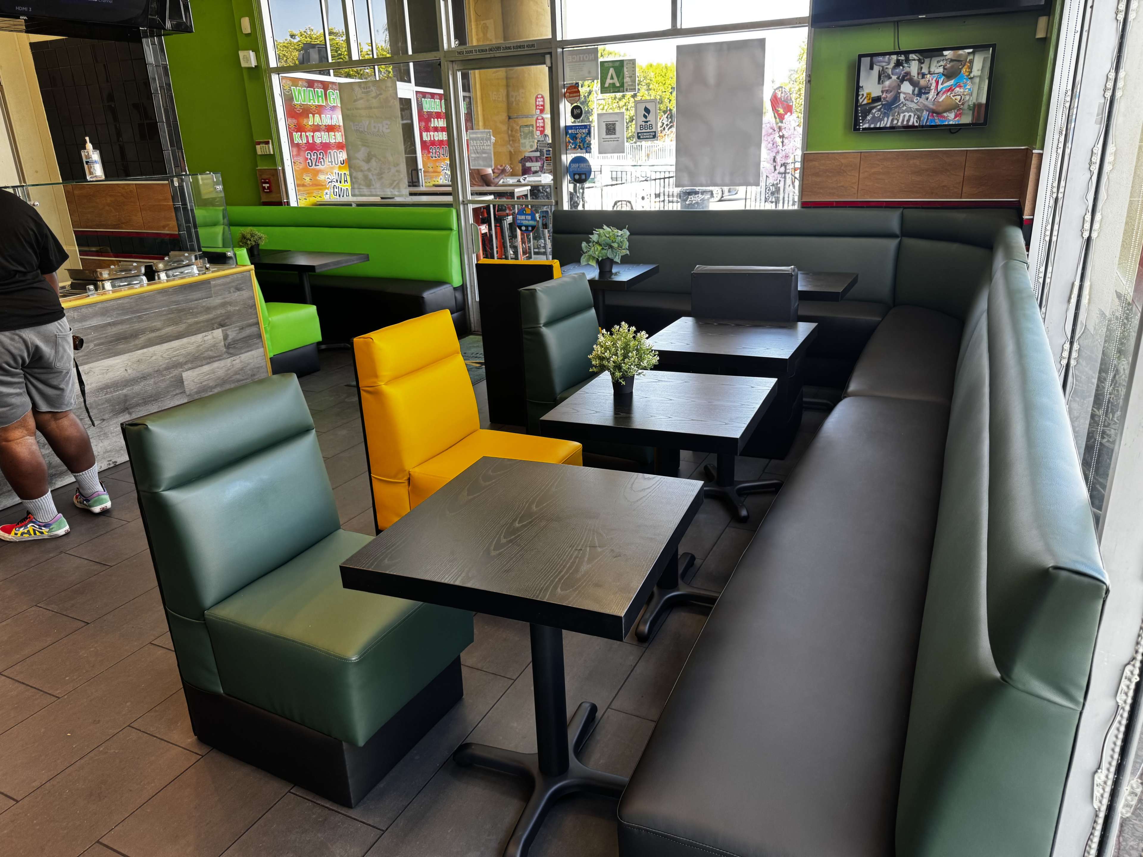 The image shows a modern café interior with several tables and seating arrangements in green, black, and yellow colors.