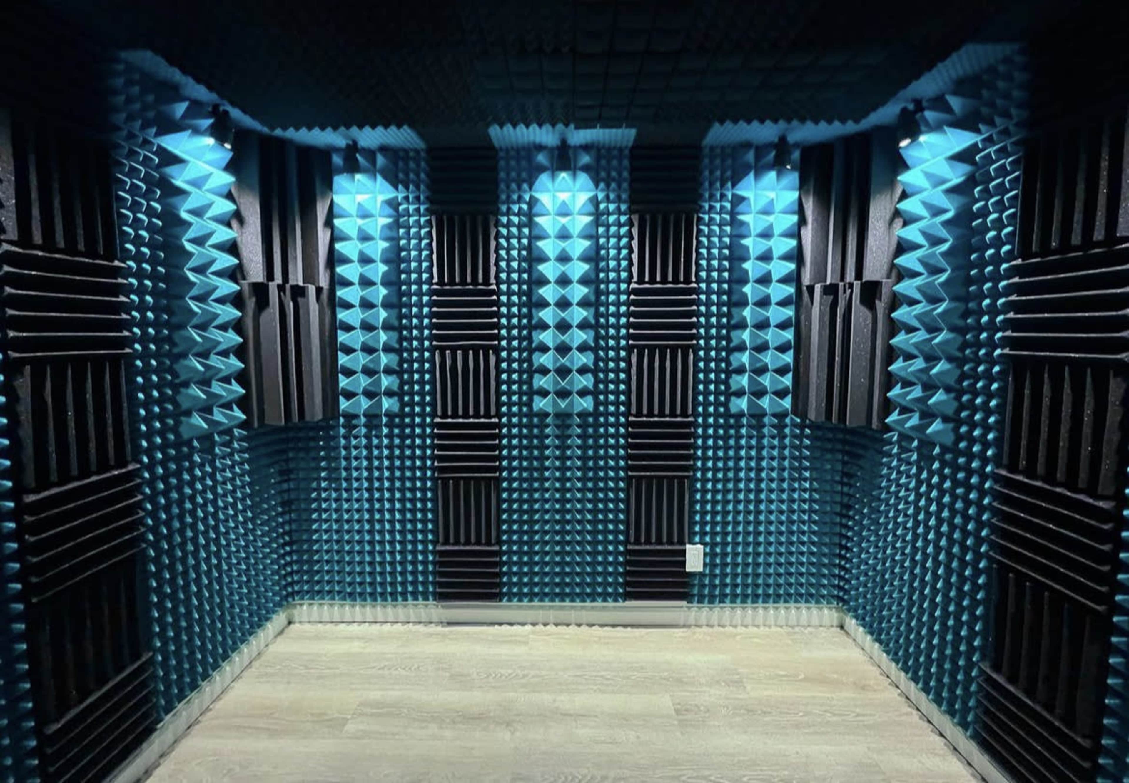 A soundproof room with blue and black acoustic foam panels arranged on the walls.