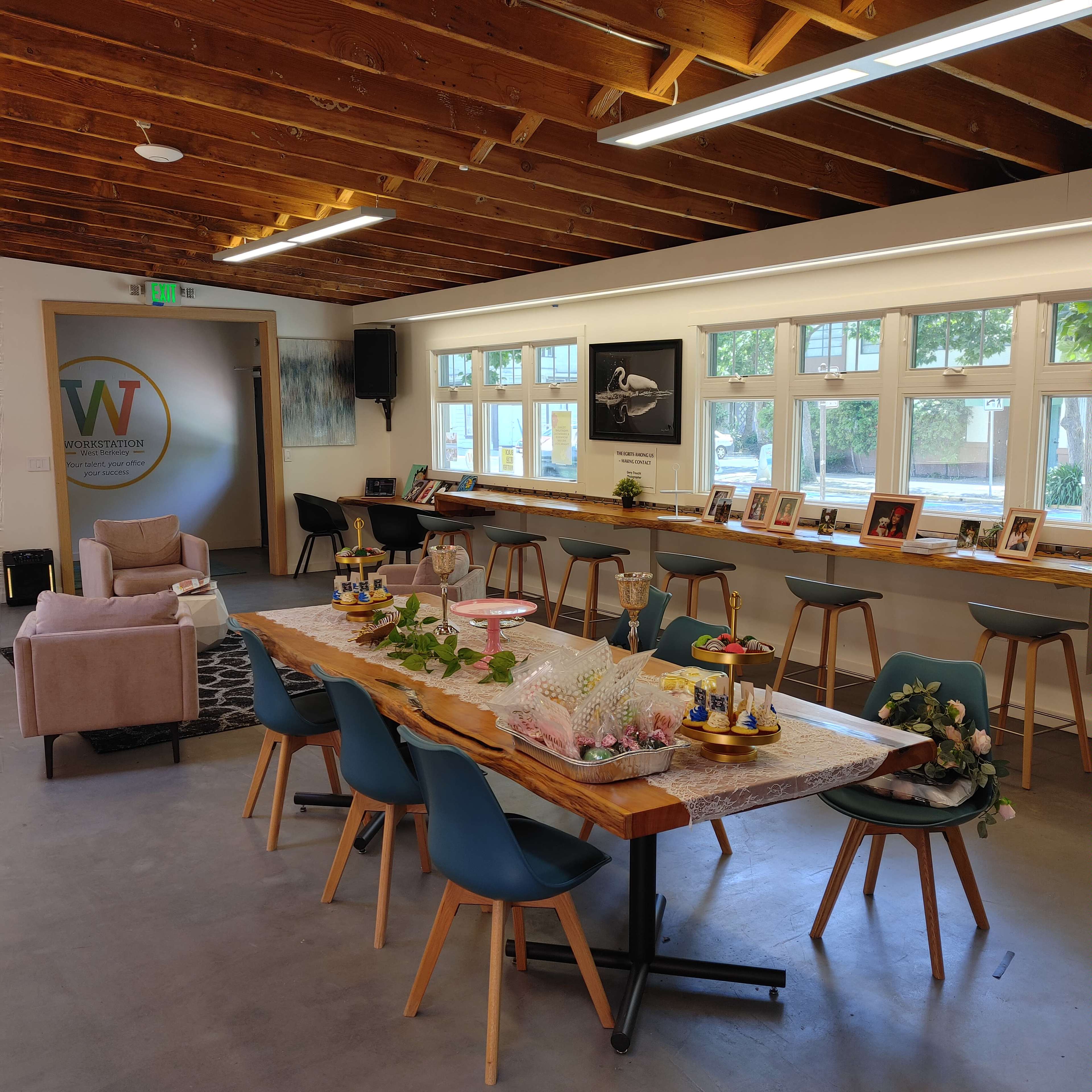 A spacious room with a long table set for a gathering, featuring decorative items and a variety of seating arrangements.