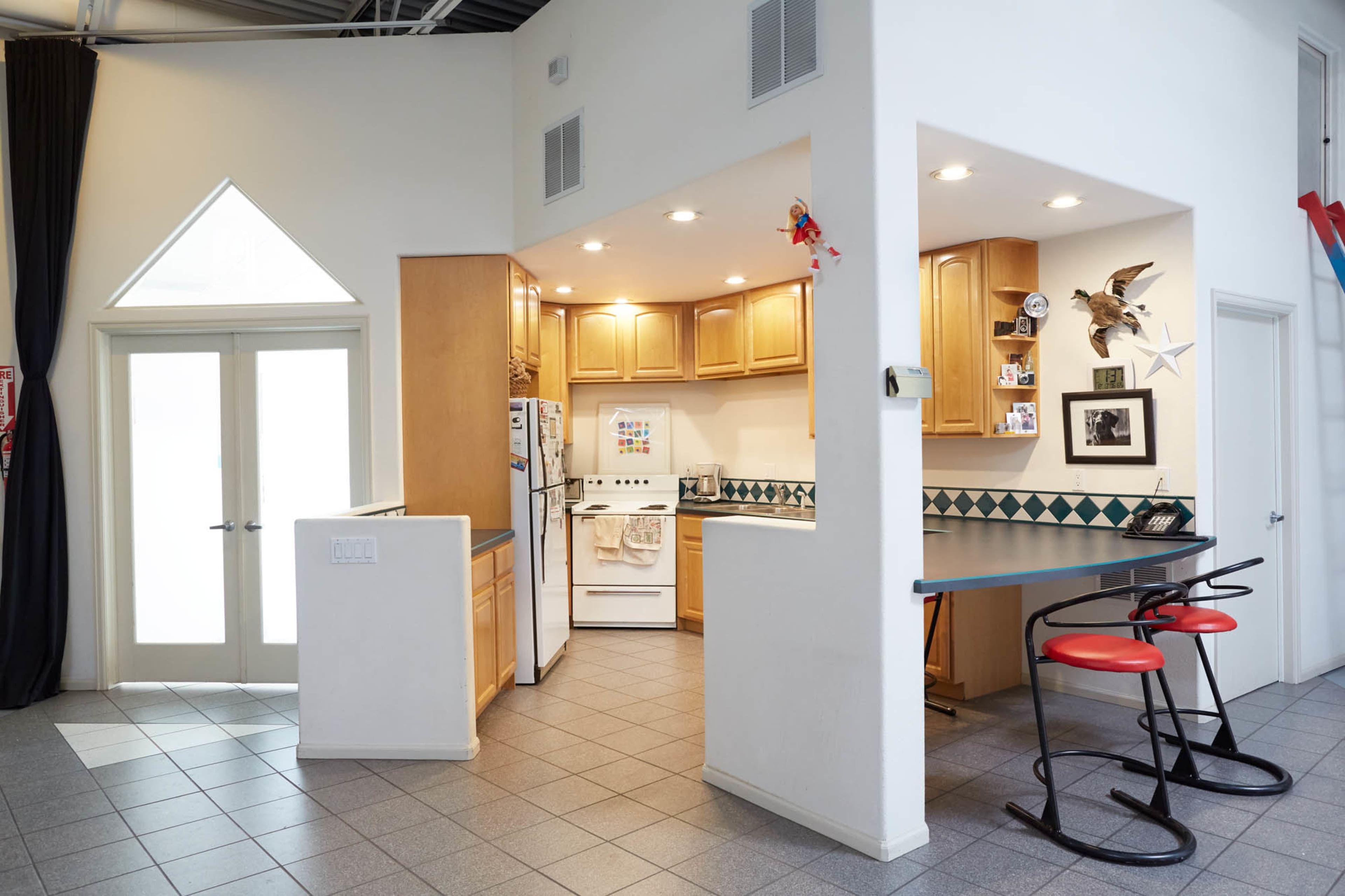 A modern kitchen area with wooden cabinets, a white stove, and a bar counter with red stools, adjacent to a dining space featuring doors that open to an outdoor area.