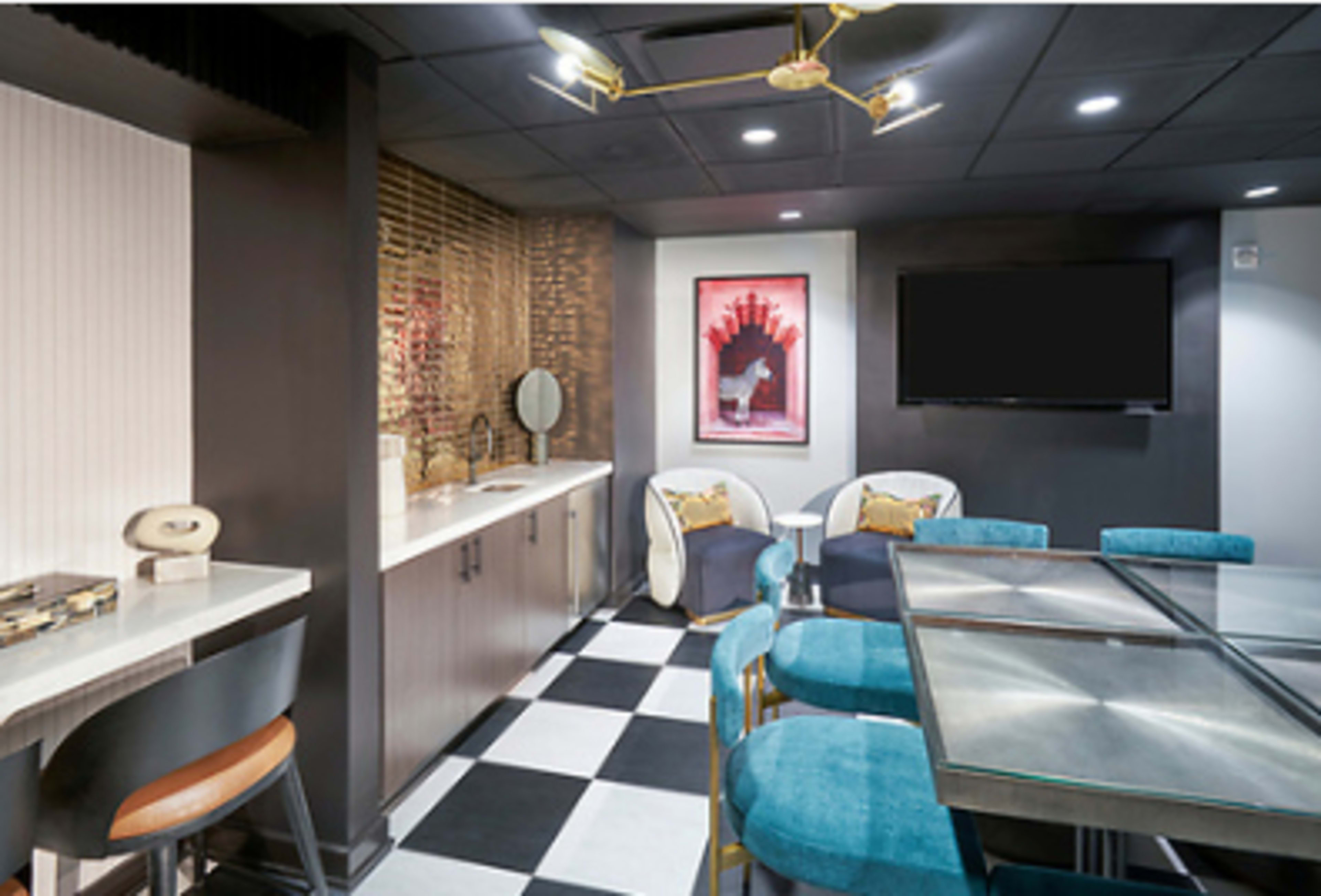 The image shows a modern, stylish lounge area featuring a bar, a large glass dining table, plush chairs, and decorative wall art.