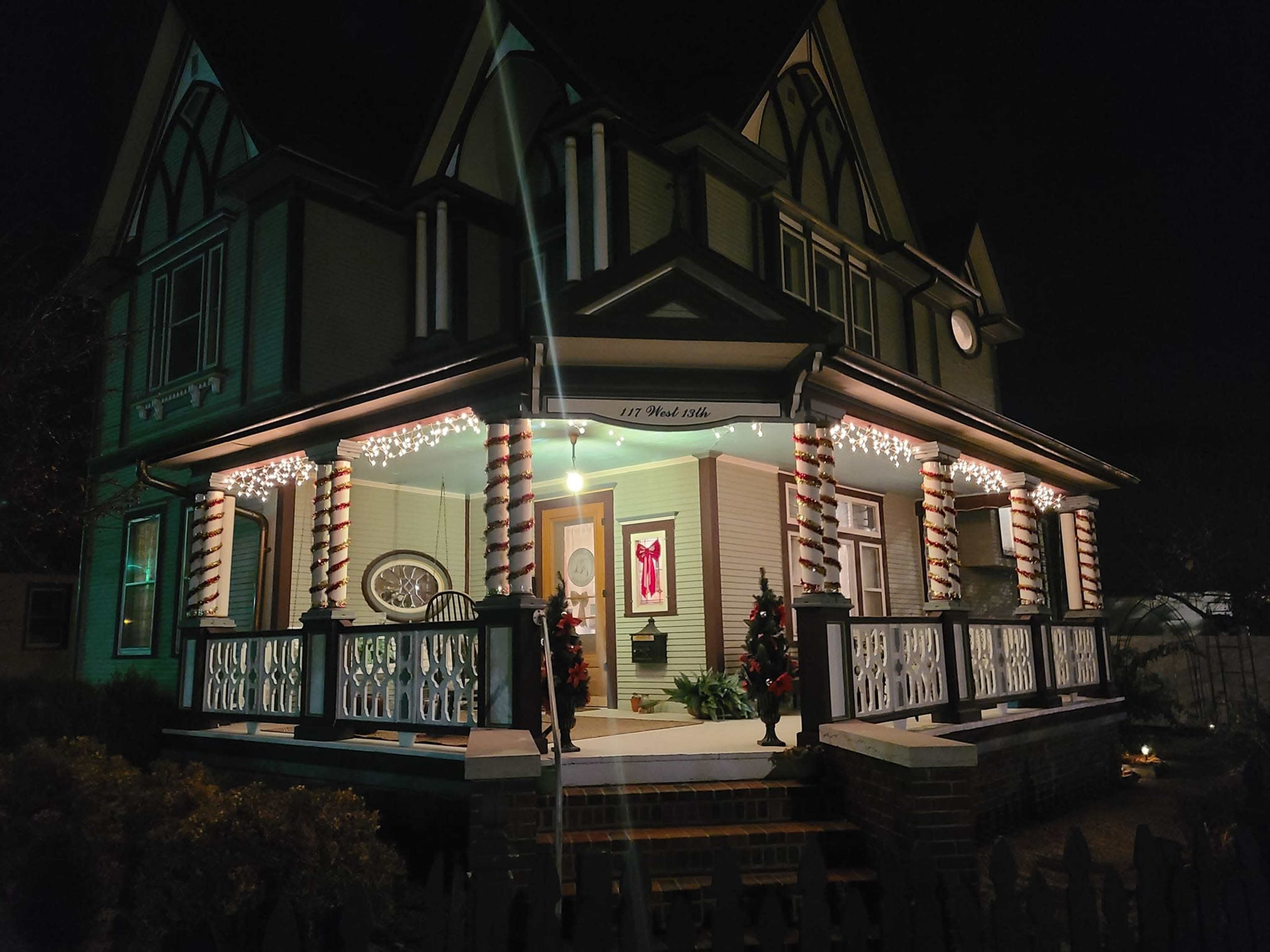 The house features a porch decorated with candy cane-striped columns and string lights, set against a dark night sky.