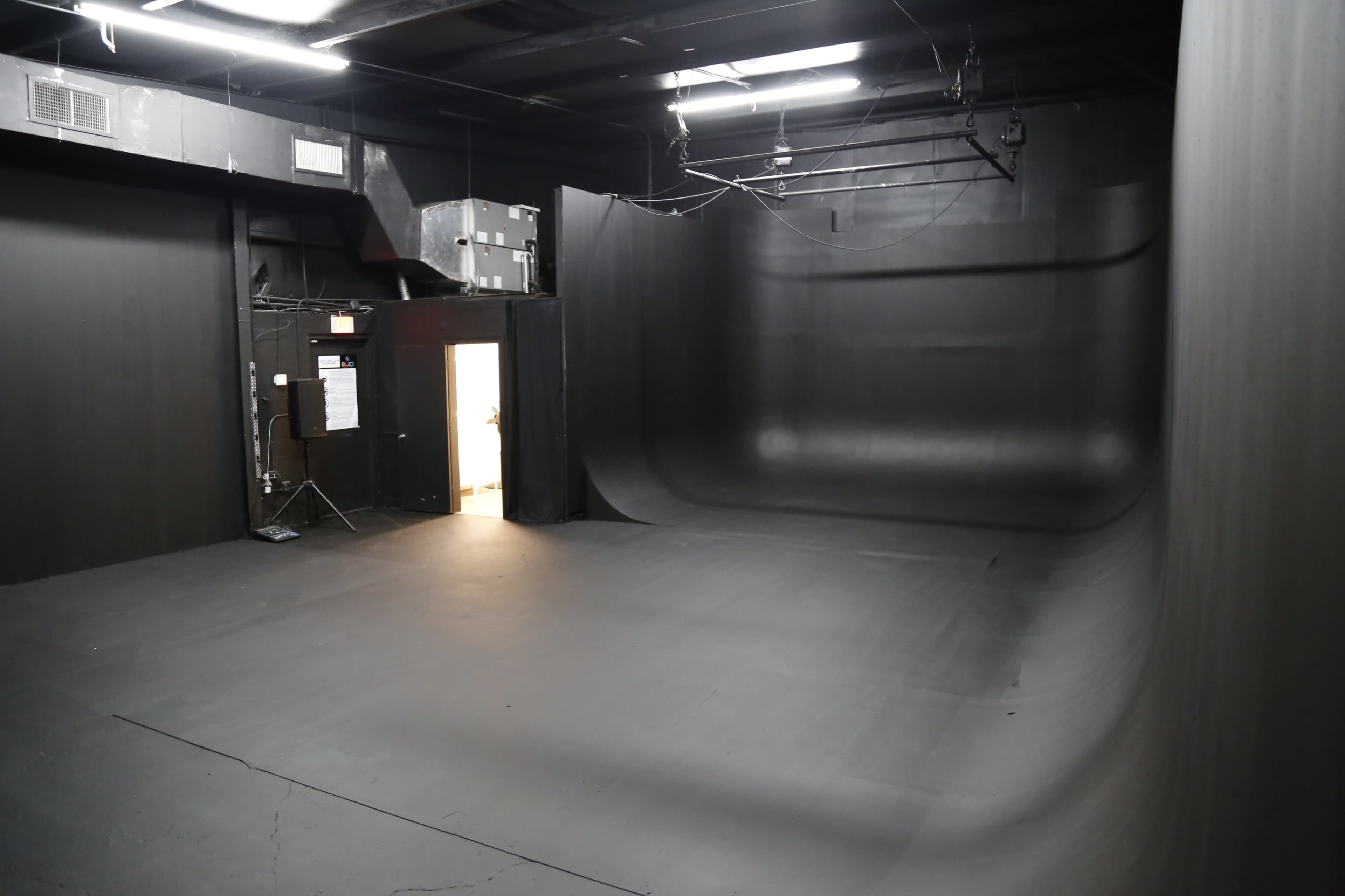 An empty black studio space with curved walls and a doorway at one end.