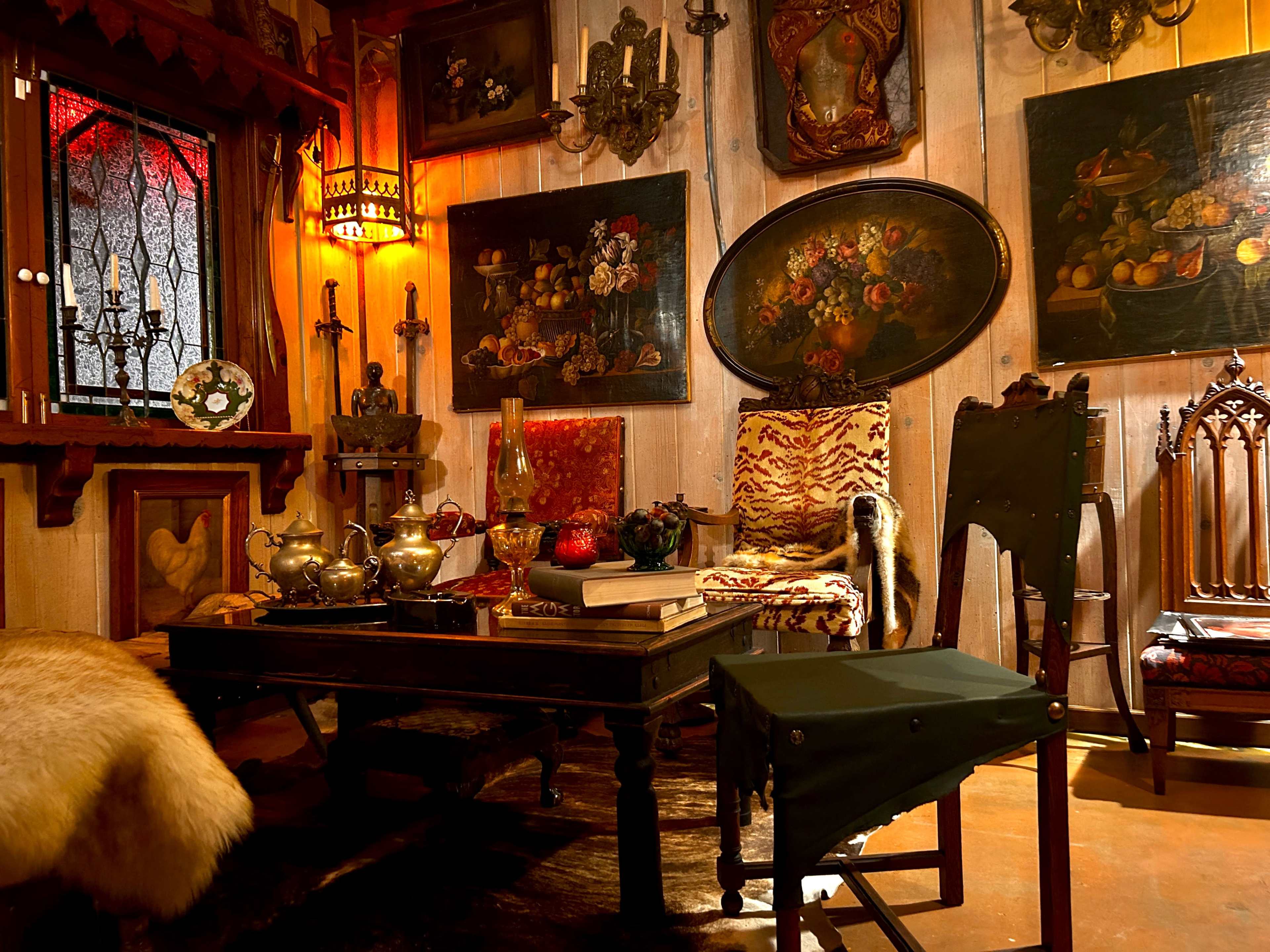 A cozy room filled with antique furniture, ornate decorations, and various paintings on the walls.
