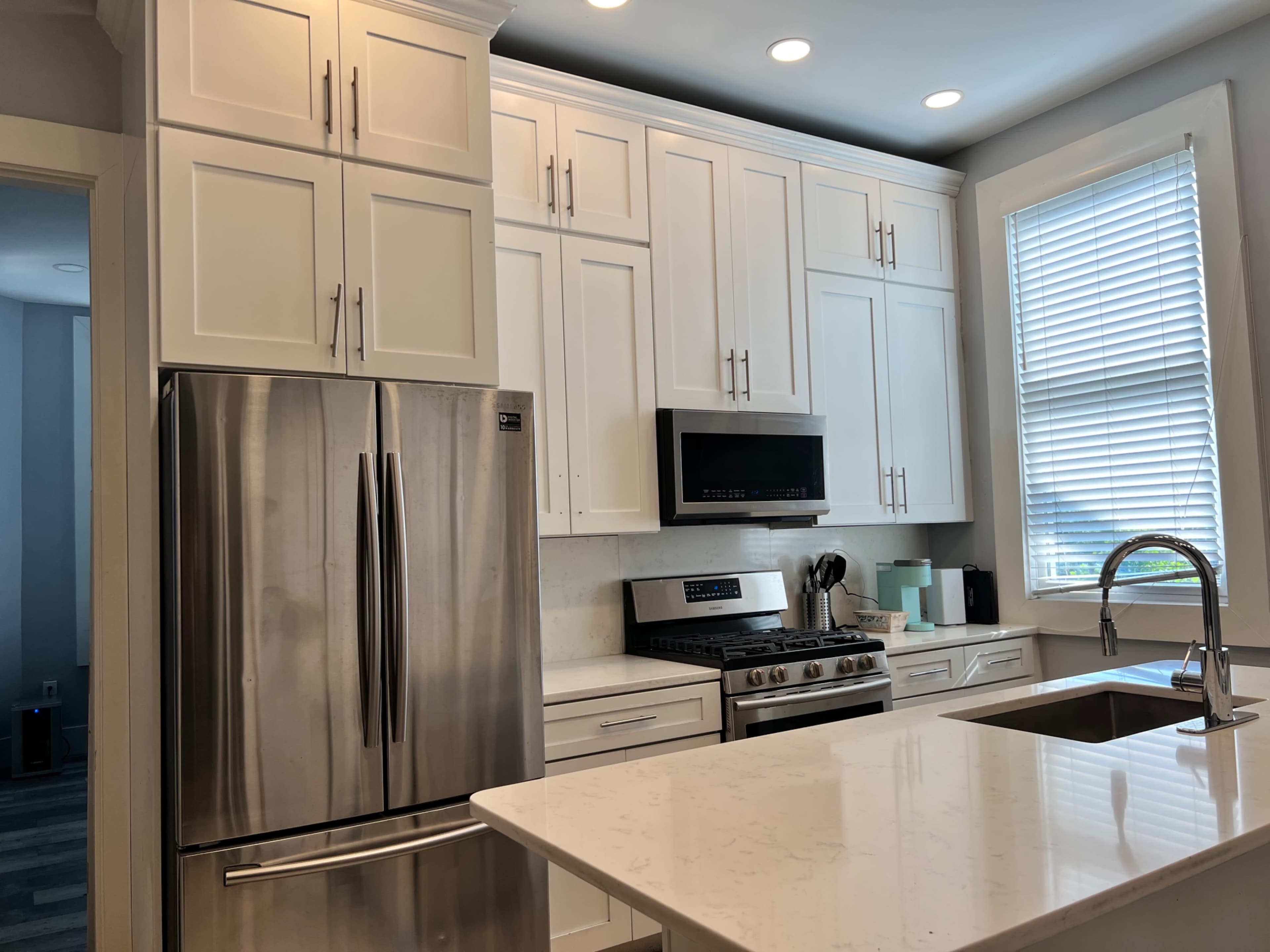A modern kitchen featuring white cabinets, stainless steel appliances, a gas stove, and a large island with a sink.