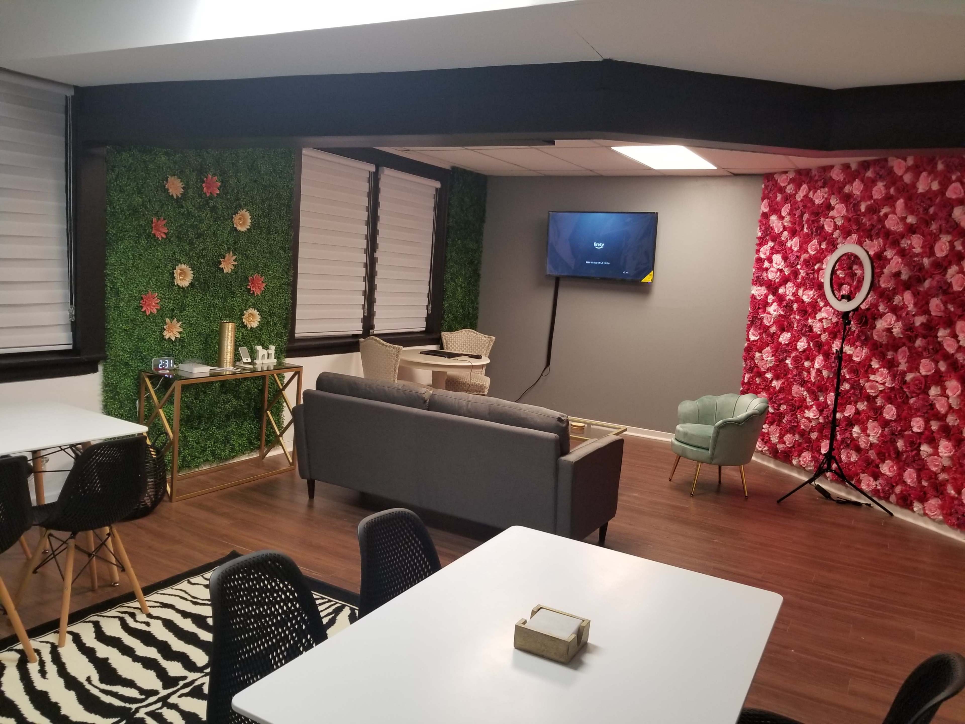 A modern room featuring green and floral accent walls, a television on one side, and a seating area with a couch and chairs.