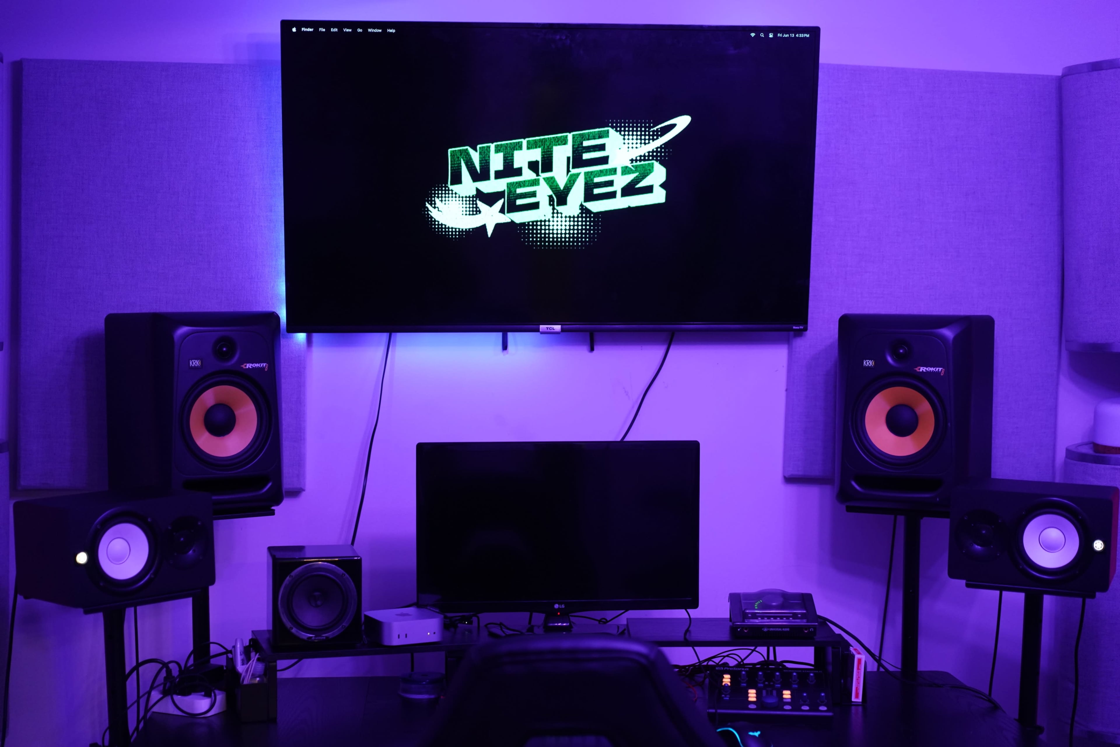 The image depicts a music production setup featuring a large screen displaying "NITE EYEZ," flanked by studio monitors and a computer workstation.