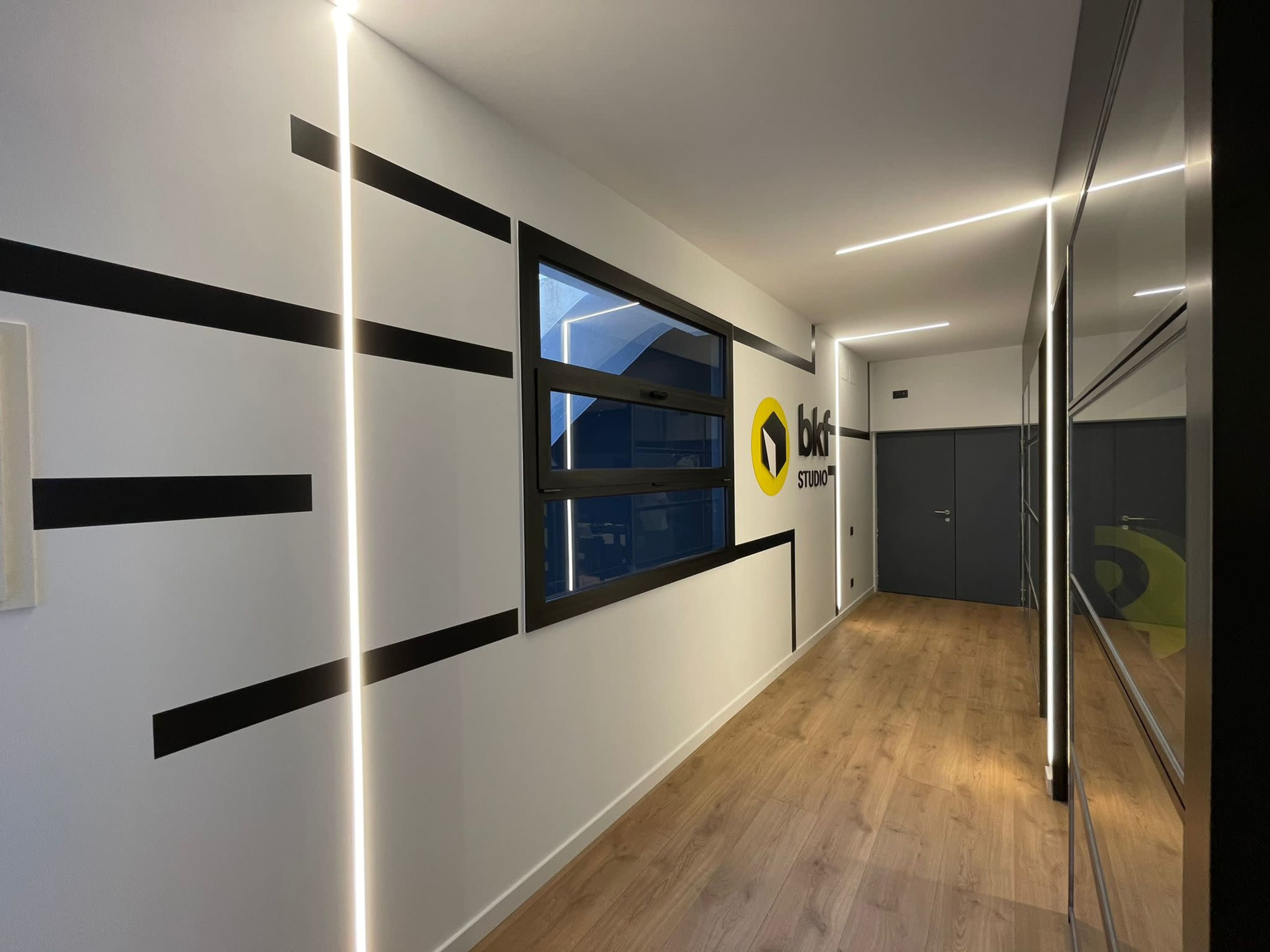 A modern hallway with a sleek design, featuring wall graphics and large windows.