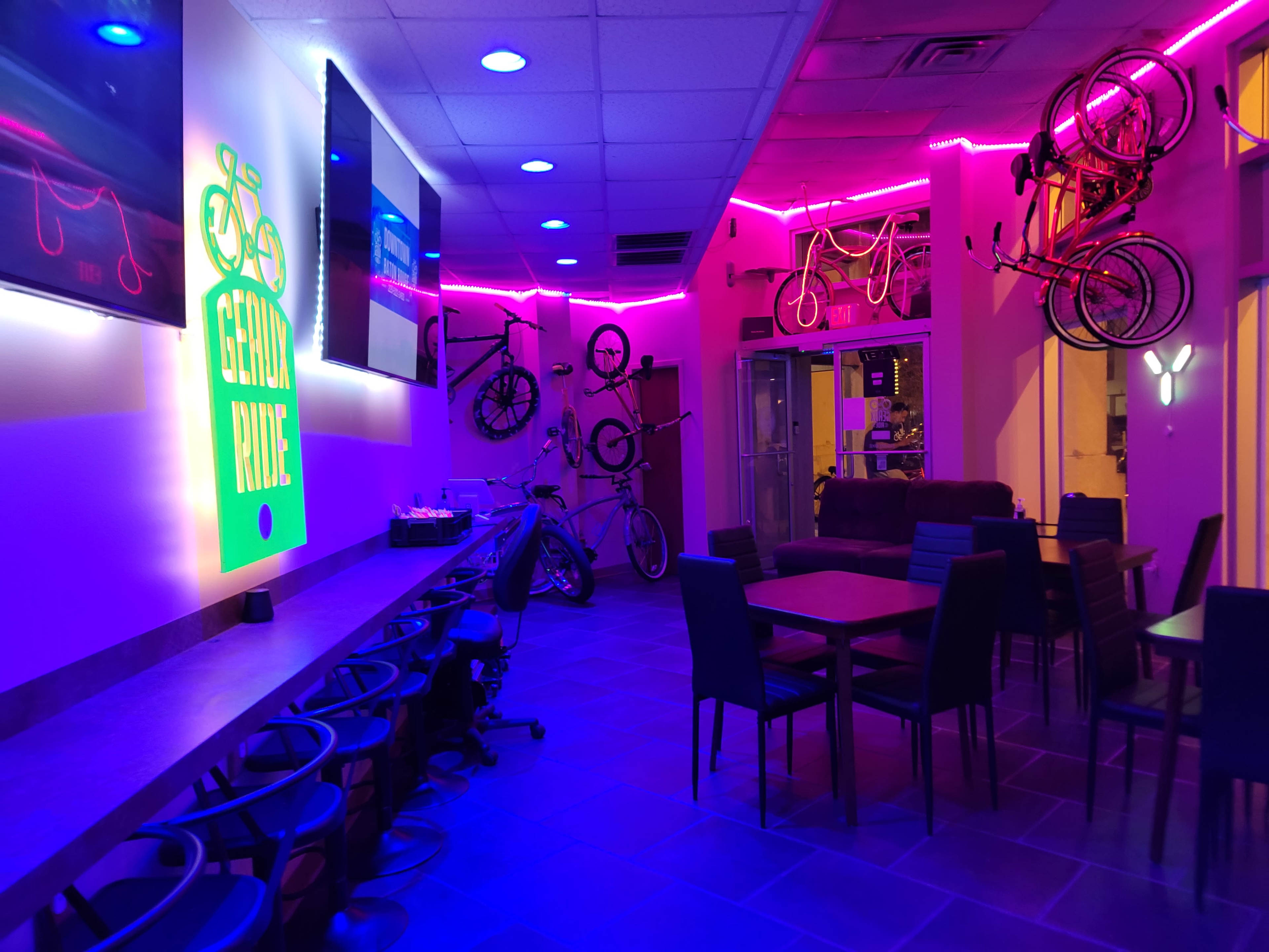 A brightly lit bicycle-themed café with neon lights, bicycle decorations on the walls, and seating areas.