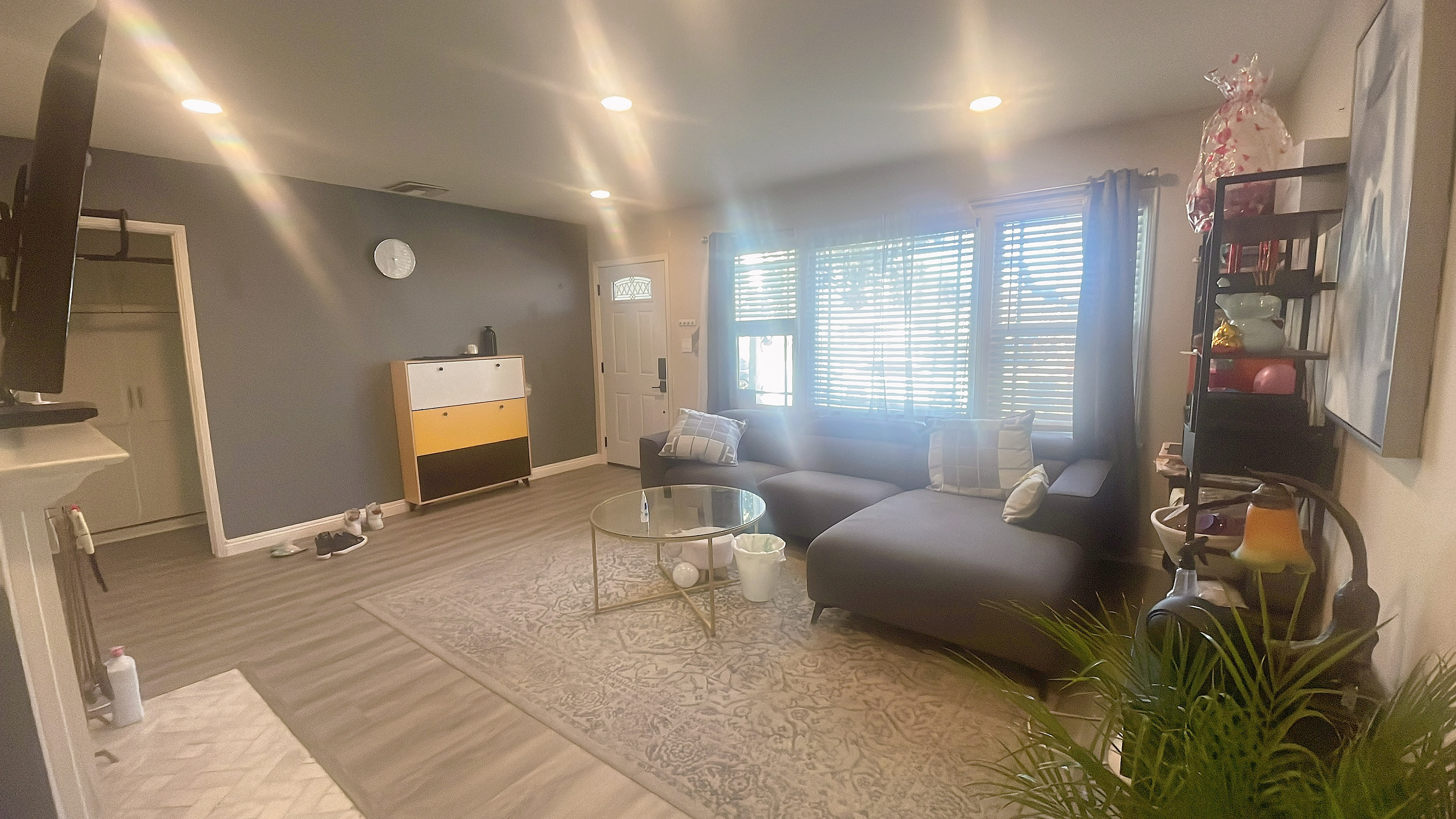 A modern living room with a gray couch, a round coffee table, and large windows allowing natural light to enter.