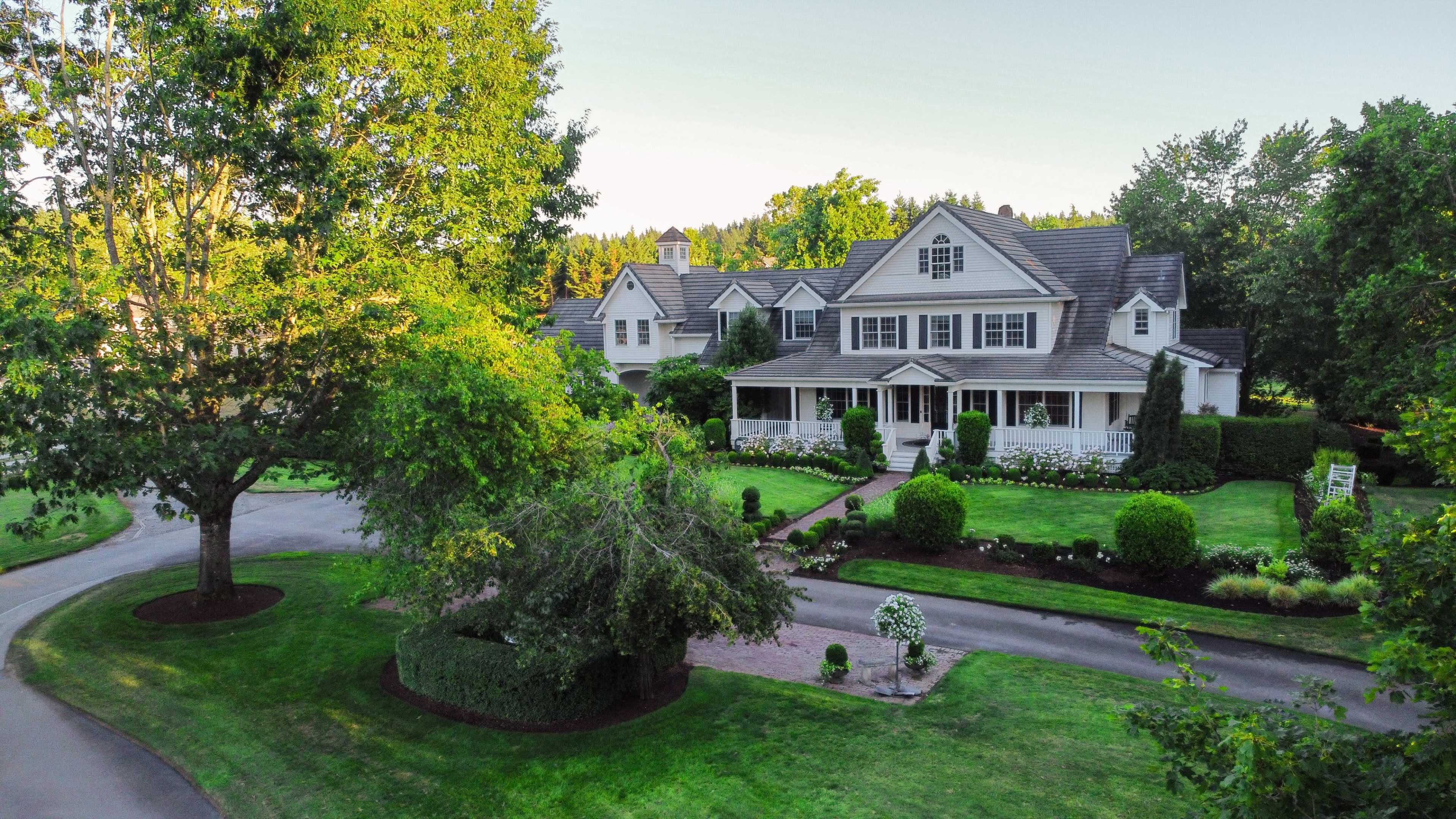 A large, two-story house surrounded by well-maintained landscaping and a circular driveway.