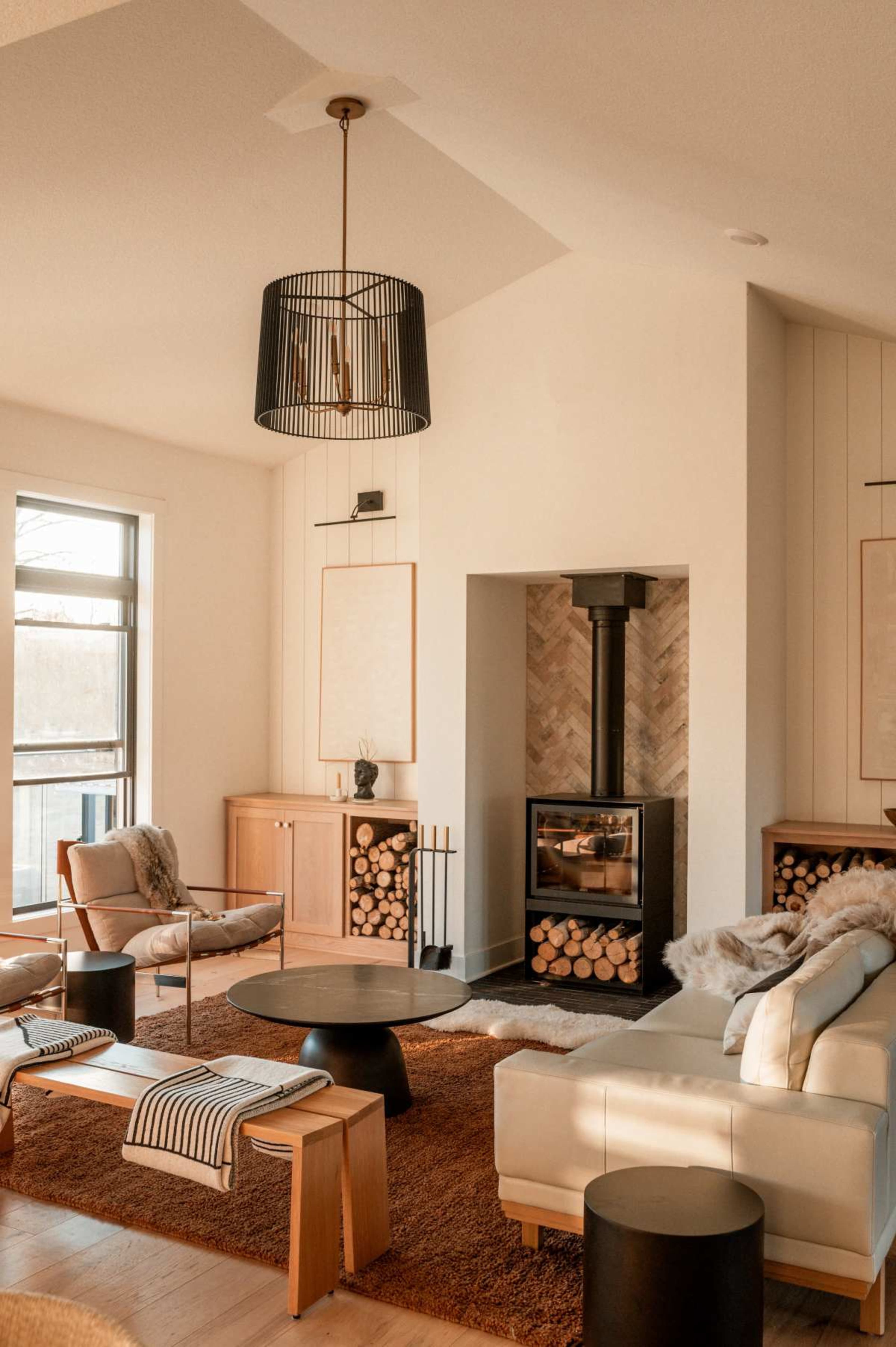 The living room features a modern design with a fireplace, two armchairs, a round coffee table, and a cozy rug.
