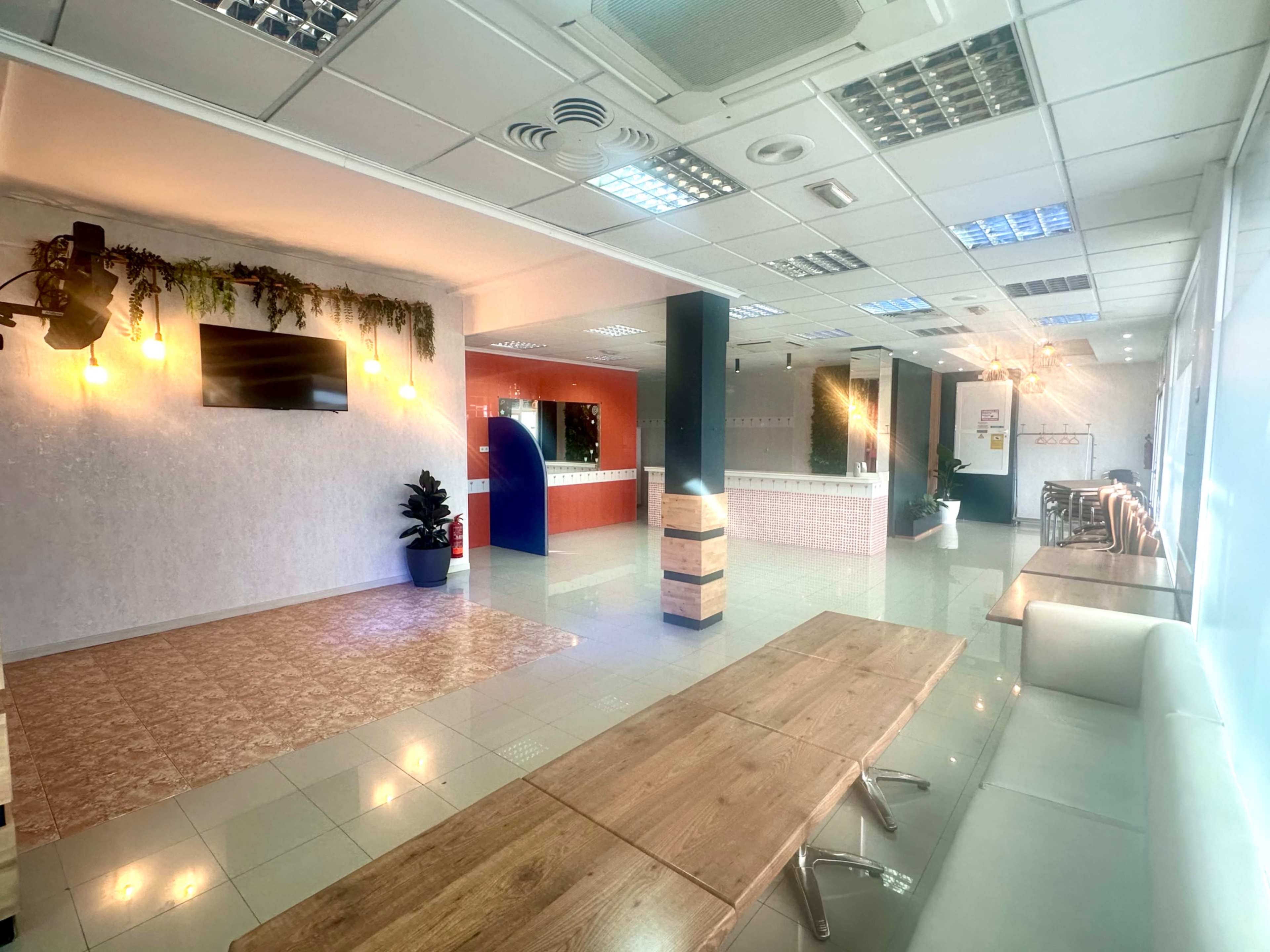 The image shows a spacious, modern office interior with a seating area, a reception desk, and decorative lighting.