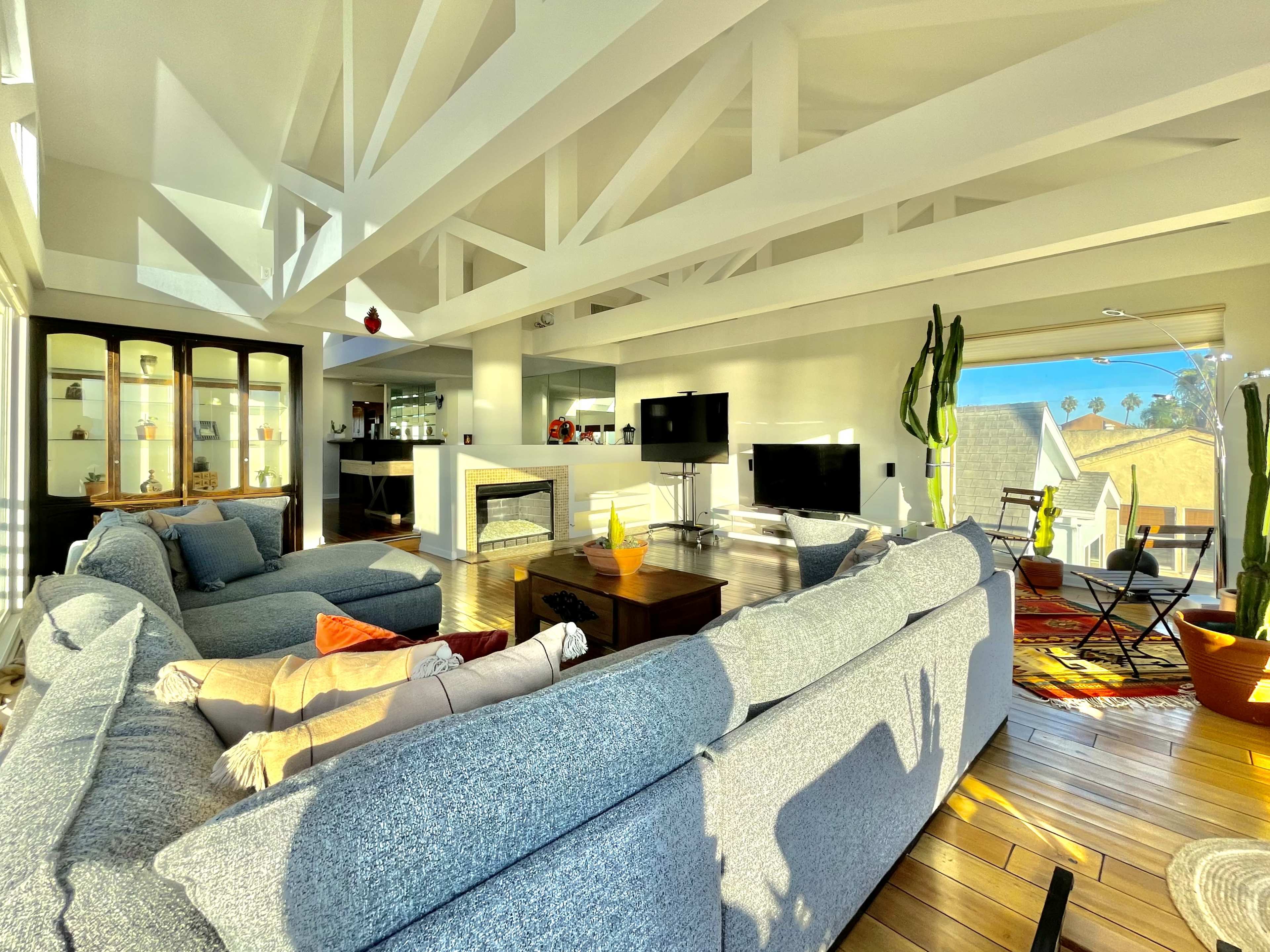 A modern living room with large windows, a fireplace, and comfortable seating arranged around a central coffee table.
