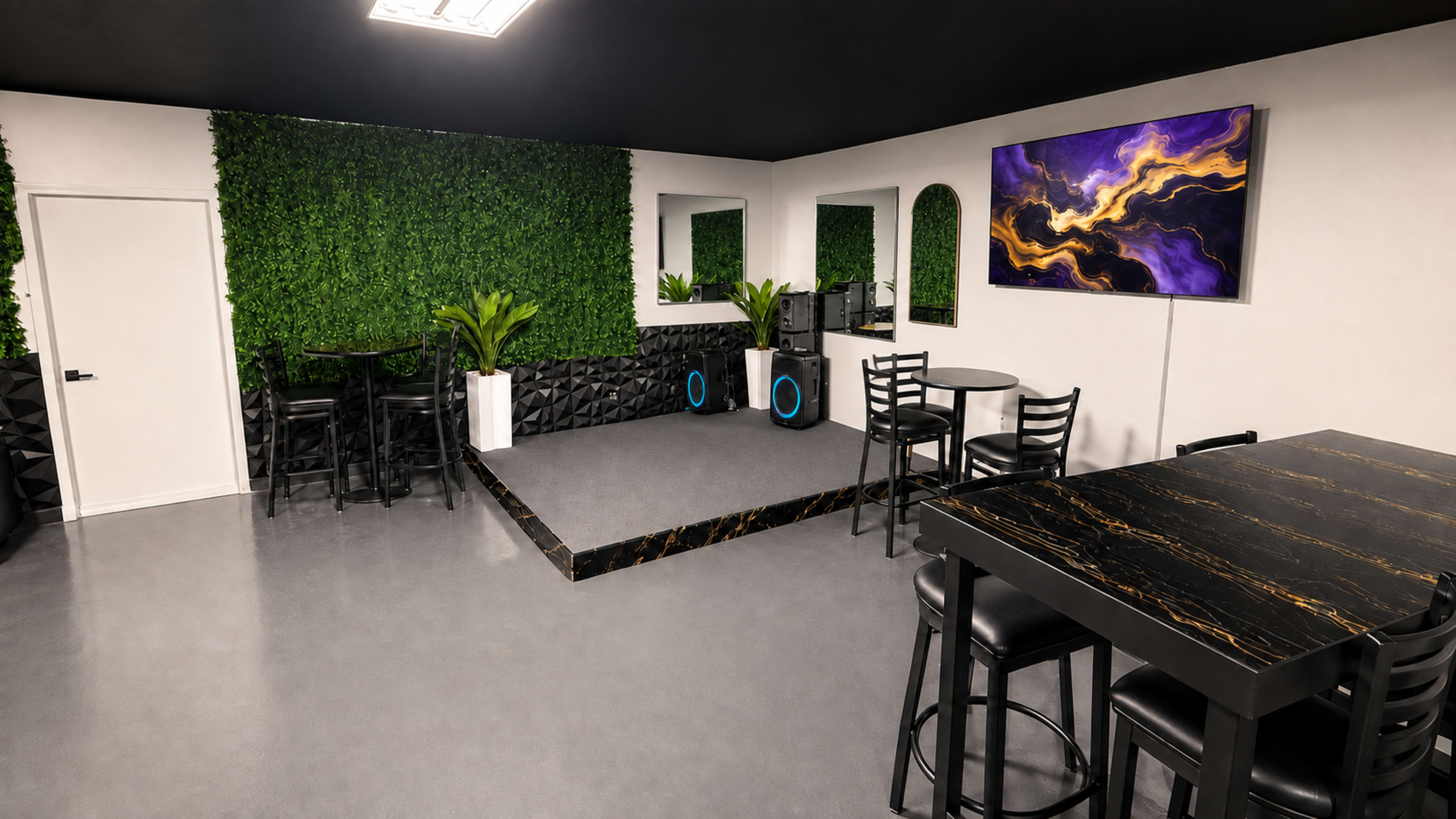 The image depicts a modern lounge area featuring black and metallic furniture, artificial greenery on the walls, and a large abstract painting hanging above a sleek console.