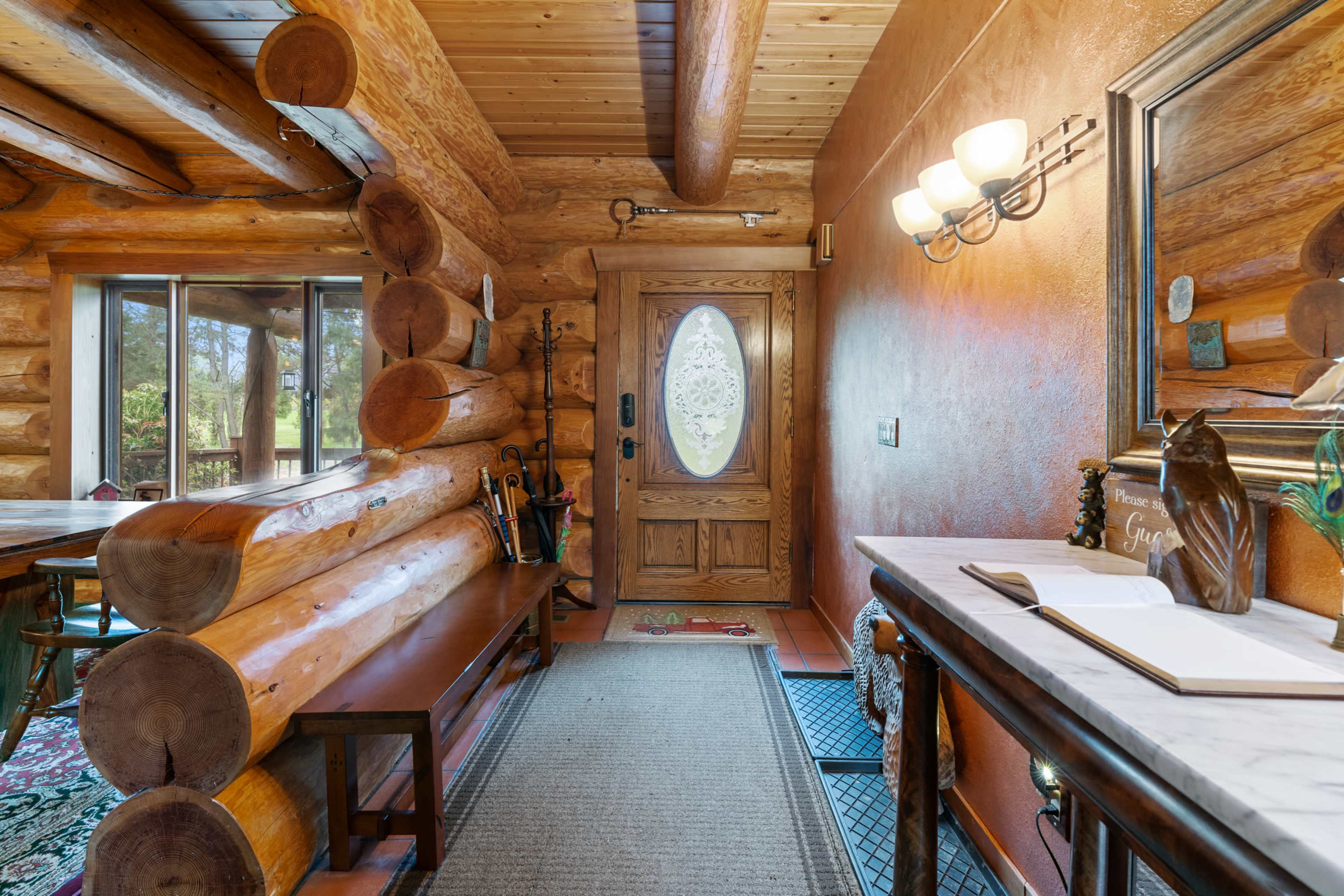 The image shows a log cabin entryway featuring a wooden door, a stone floor, and rustic wooden accents.