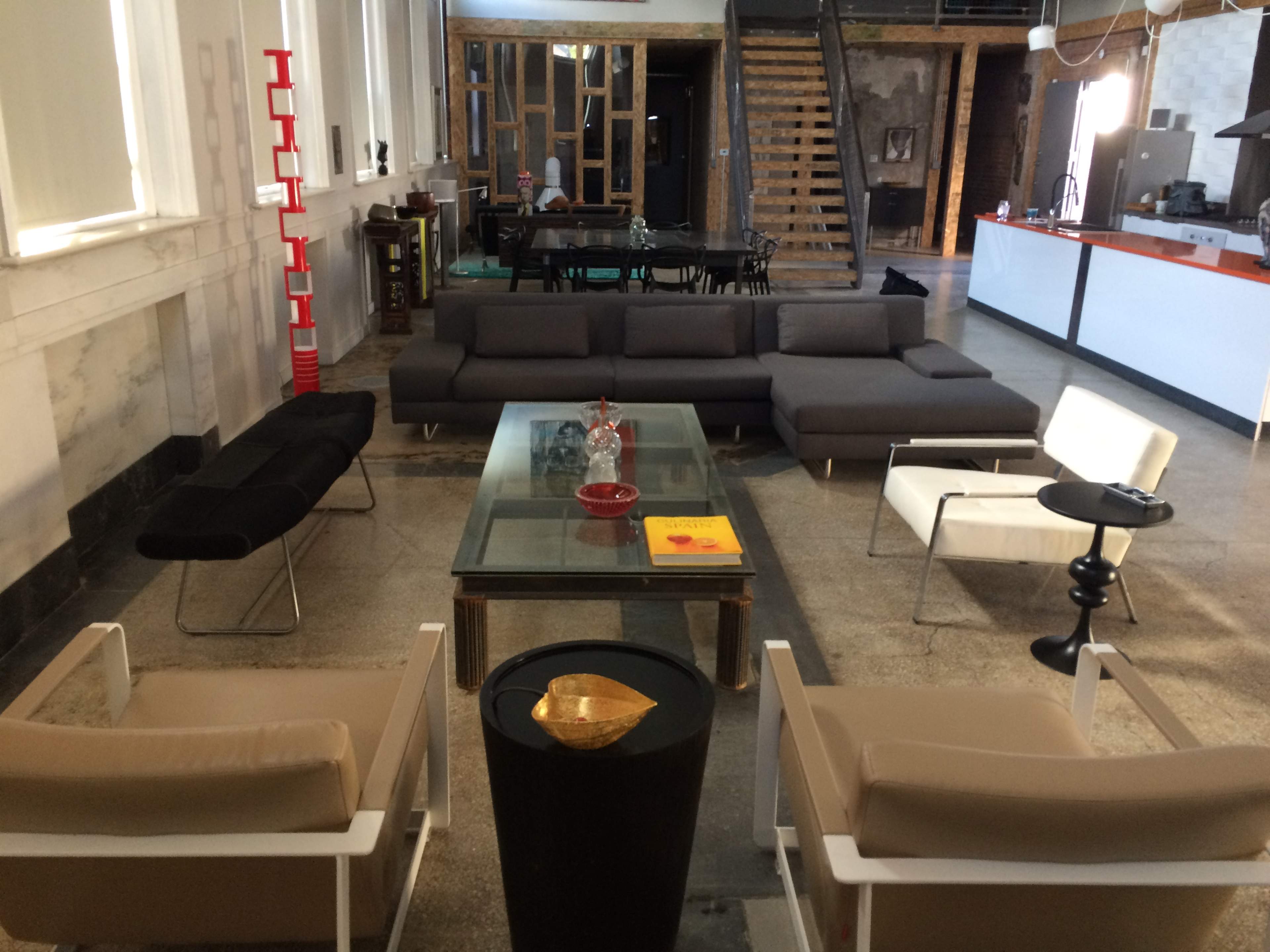 A spacious interior with modern seating arrangements, a glass coffee table, and a staircase leading to an upper level.