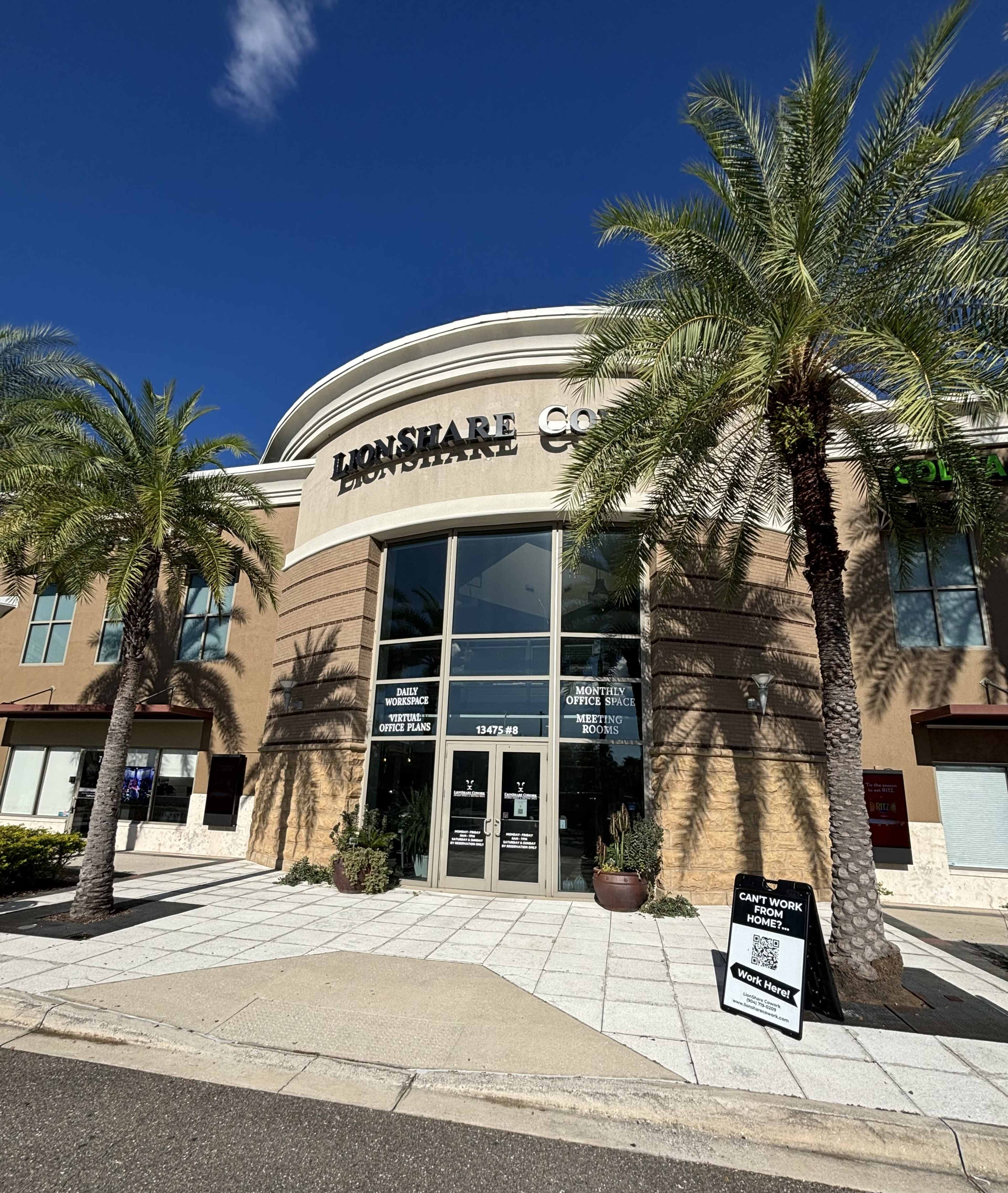 The image shows a commercial building with a prominently displayed sign for "LionShare" and palm trees lining the entrance.