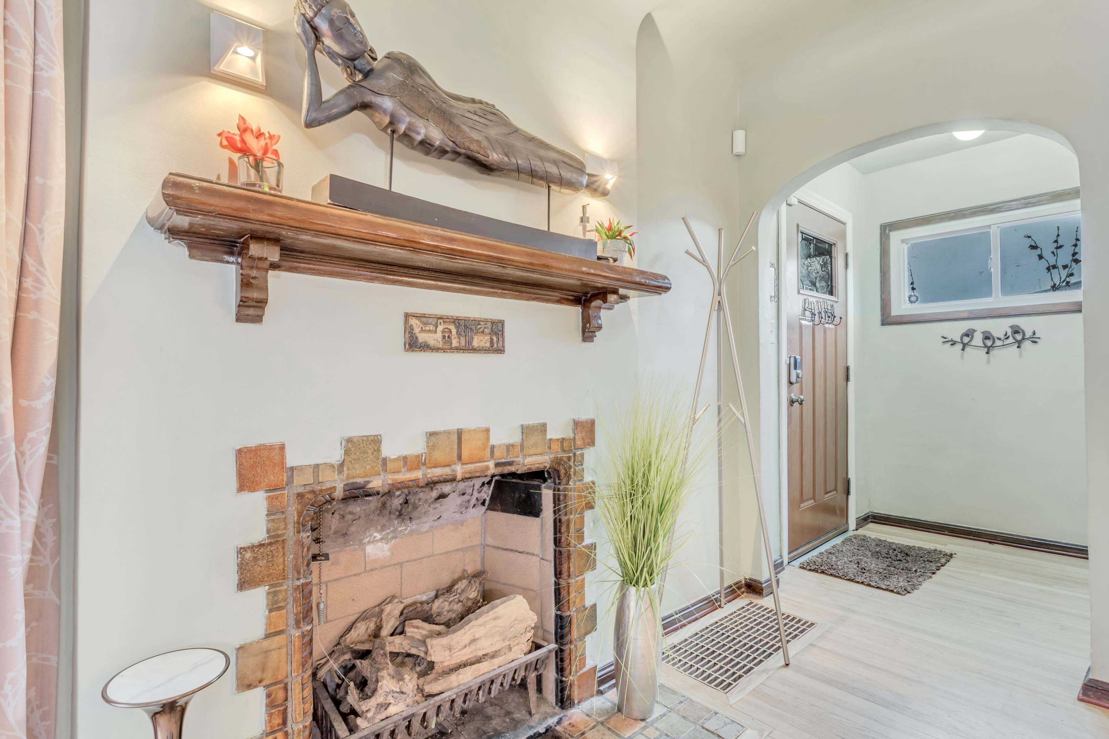 A cozy living space featuring a fireplace with a decorative mantel, a sculpture on display above it, and an adjacent entrance area.