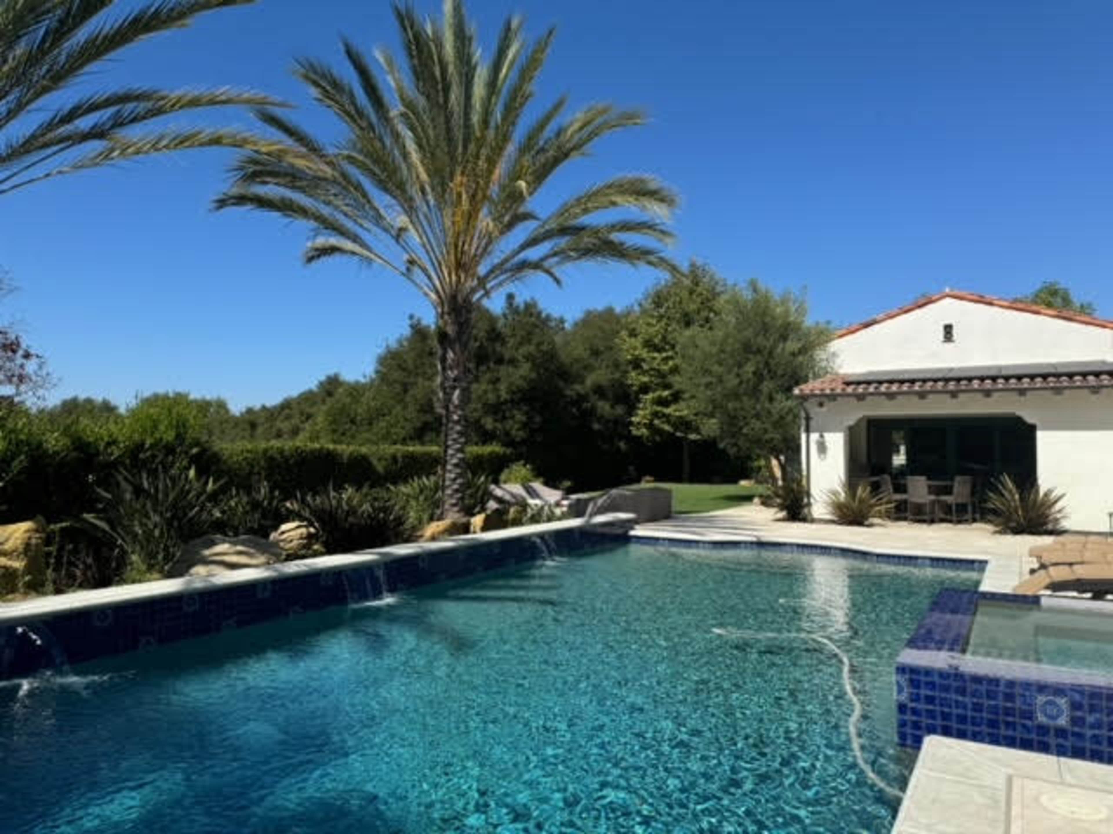 Mediterranean outdoor space with separate garden courtyard and backyard with a pool and spa.  It is surrounded by pal trees, olive trees, fruit trees, cypress trees.  Expansive and open back yard with endless views. Image in Turtle Rock, IRVINE, CA