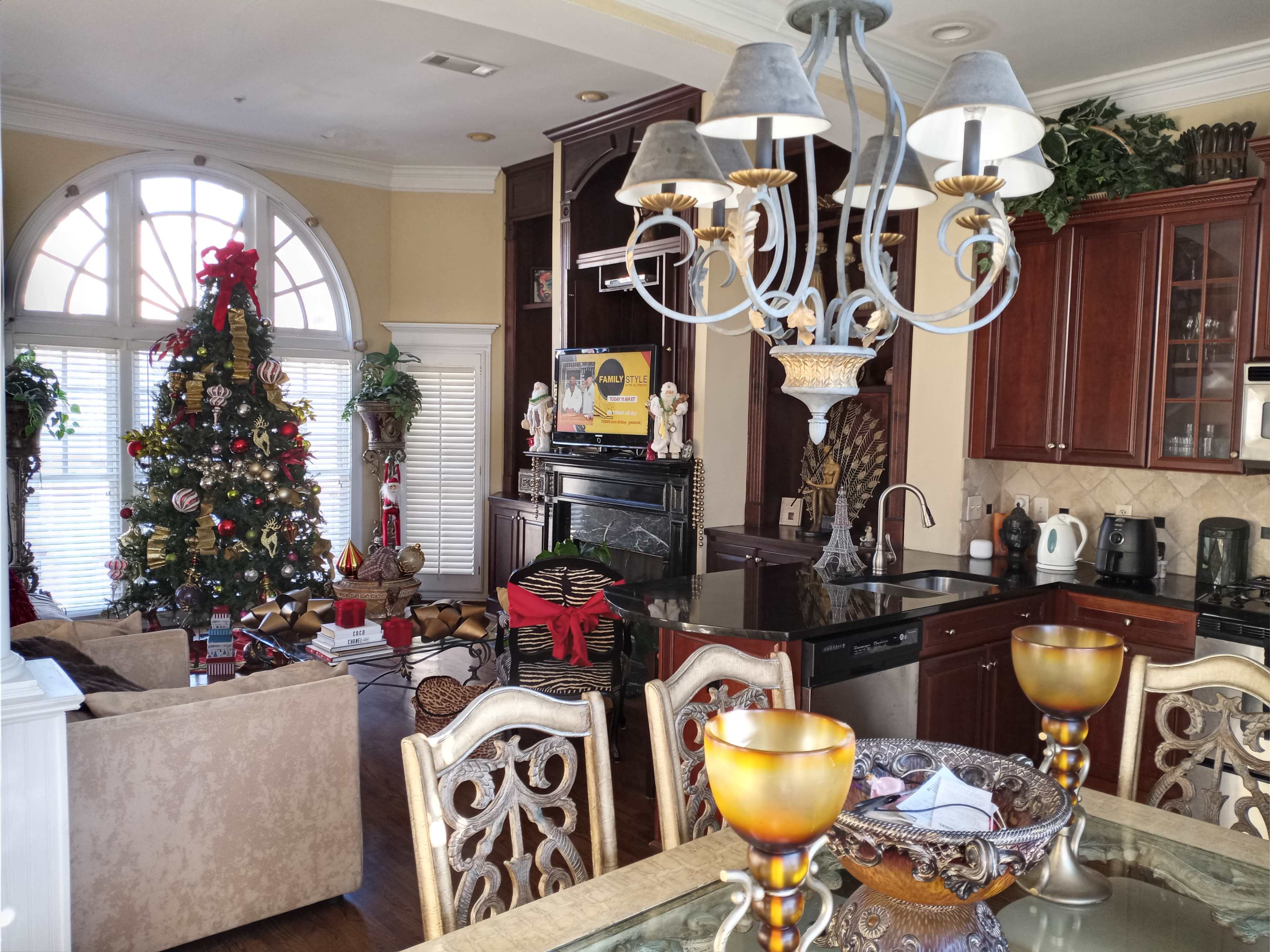 A kitchen and living room area decorated for the holidays, featuring a Christmas tree and various decorations.