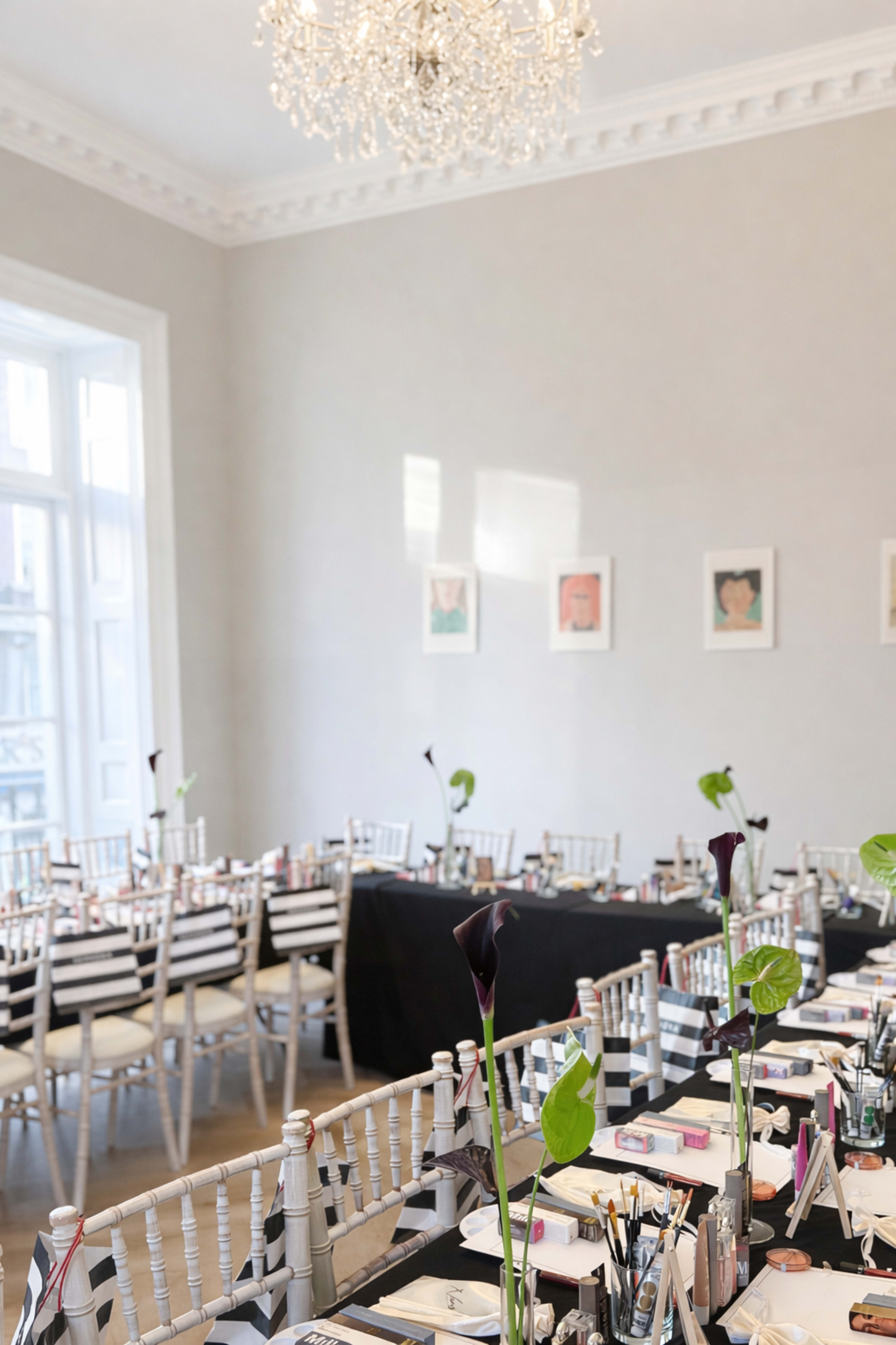 The image shows a banquet-style dining setup in a well-lit room, featuring long tables covered with black and white table settings and elegant floral centerpieces.