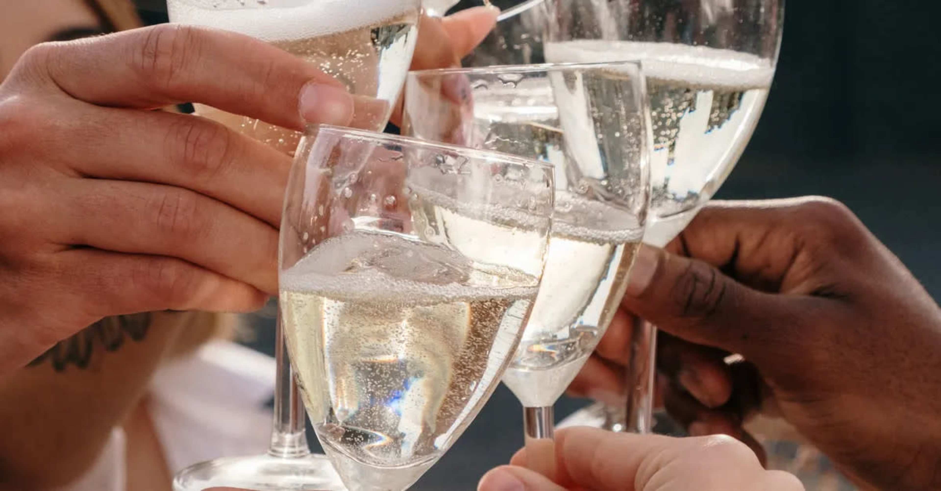 A group of people clinks champagne flutes together, celebrating with sparkling wine.