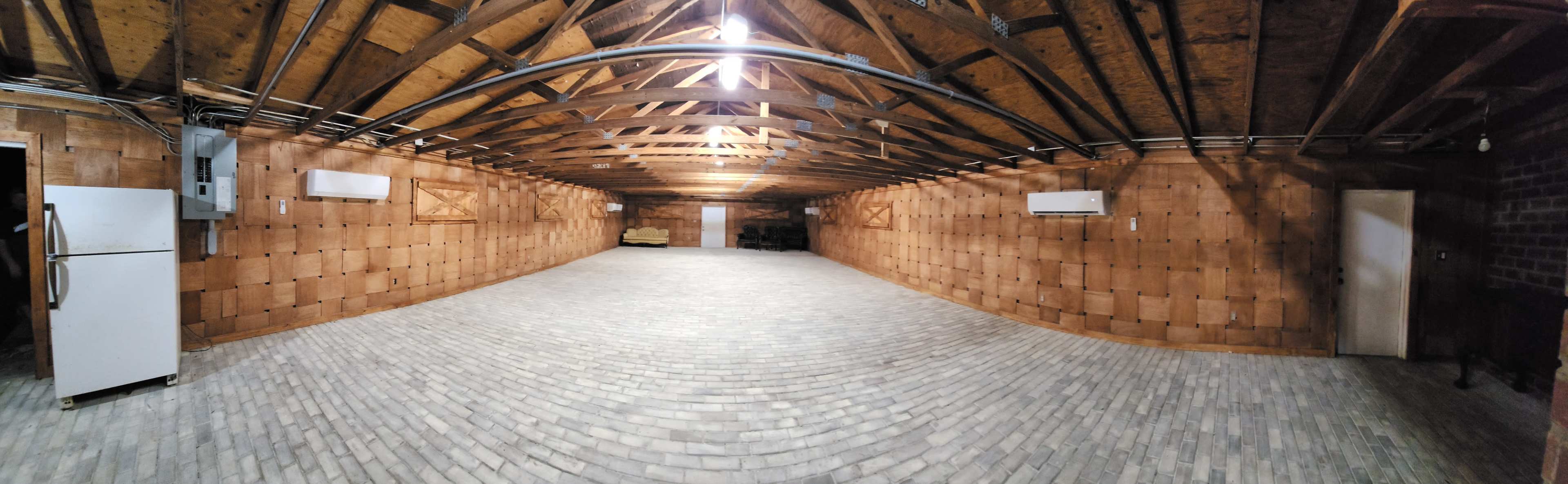 A spacious basement with a flat stone floor, wooden walls, and exposed beams in the ceiling.