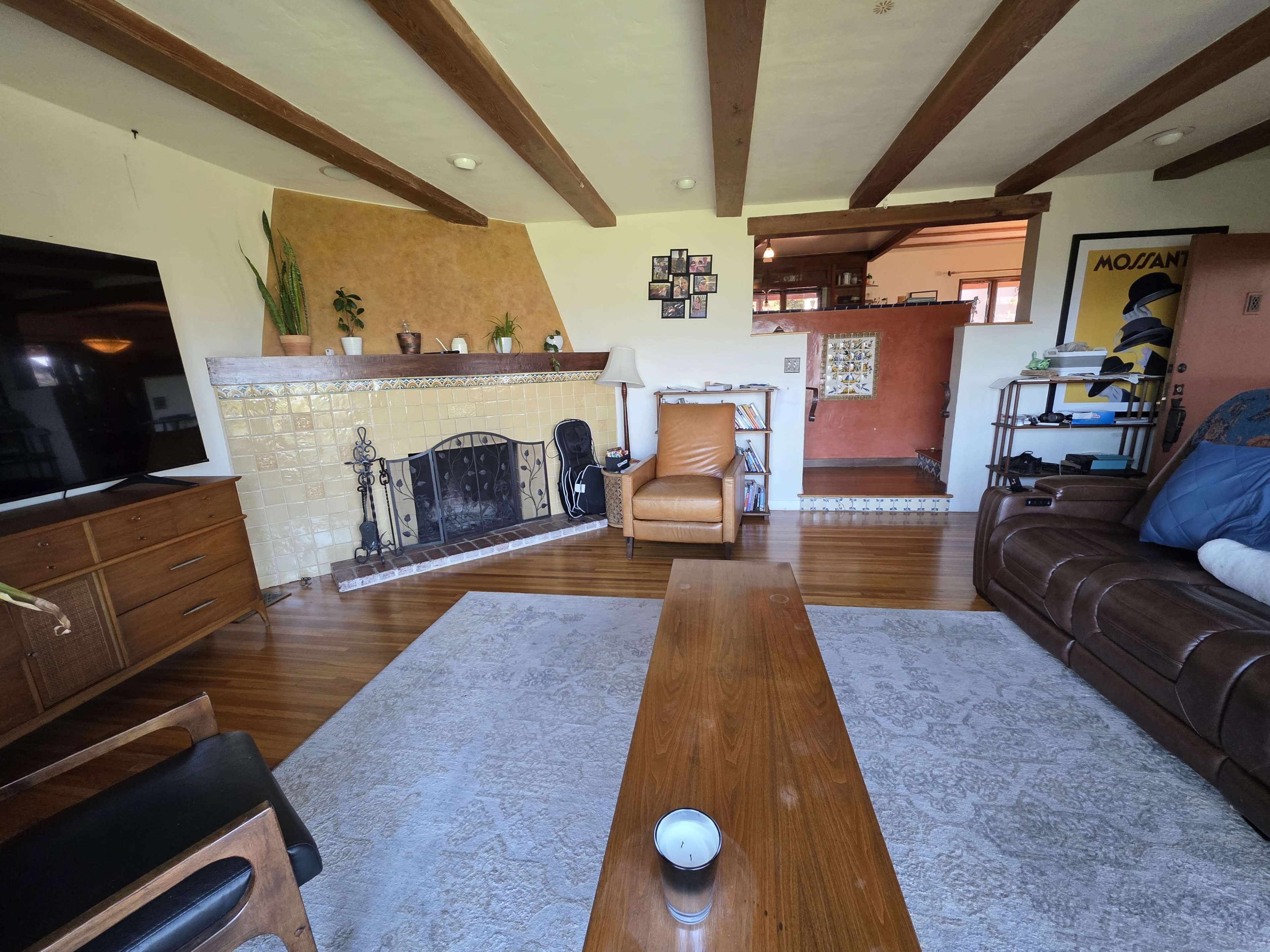 The living room features a wooden coffee table in the center, a large television on one wall, and a fireplace surrounded by decorative tiles.