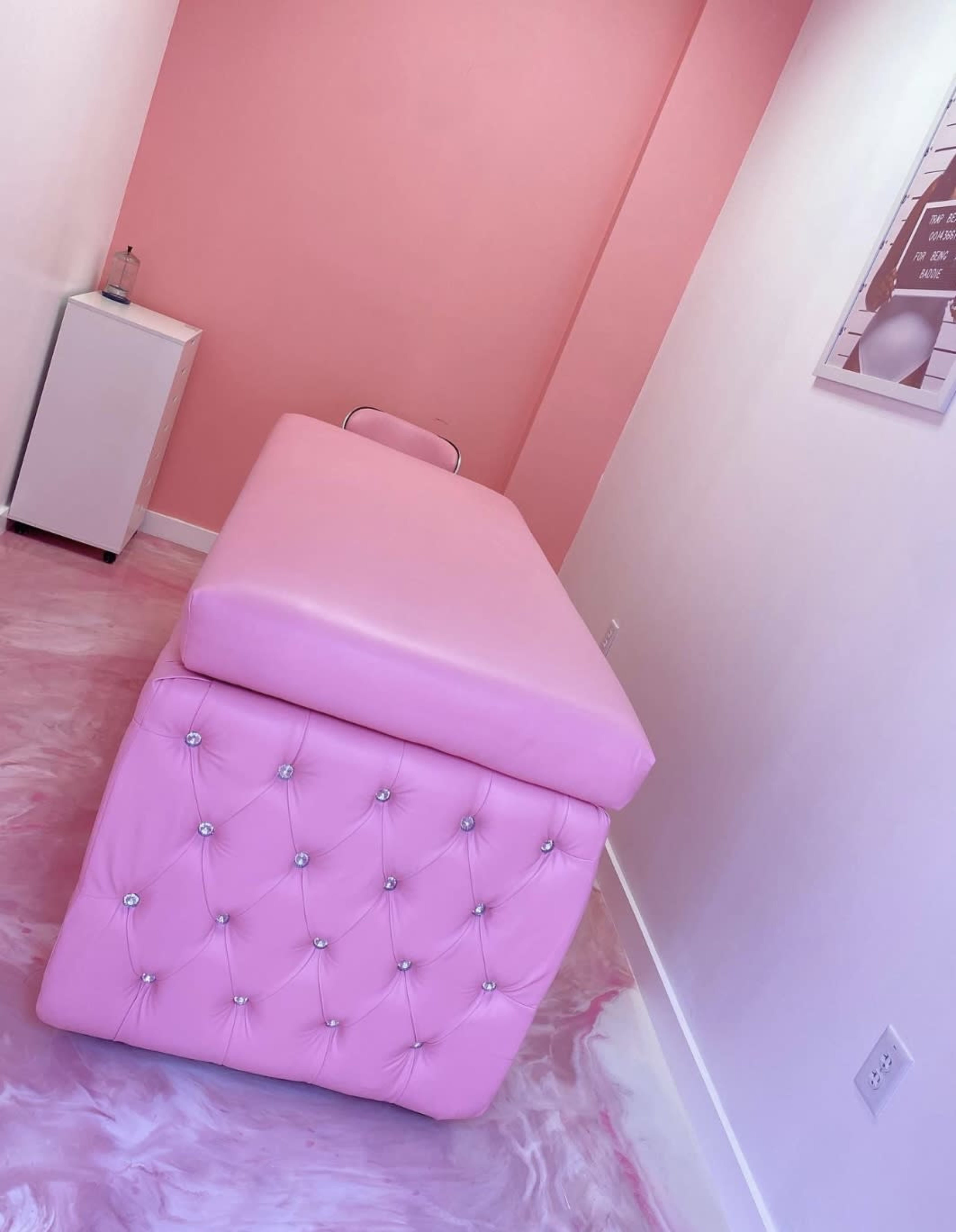 A pink examination table in a small, brightly colored treatment room with a pink and white floor.